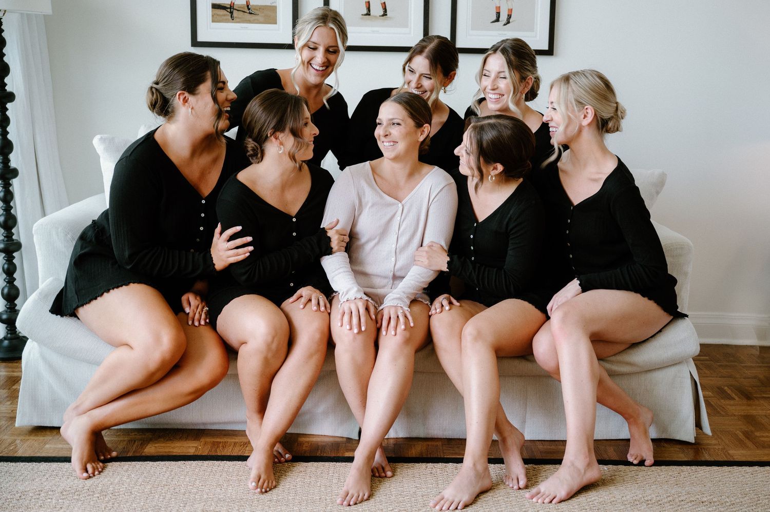A stylish wedding party of bridesmaids wearing black dresses sitting together showing their feet.