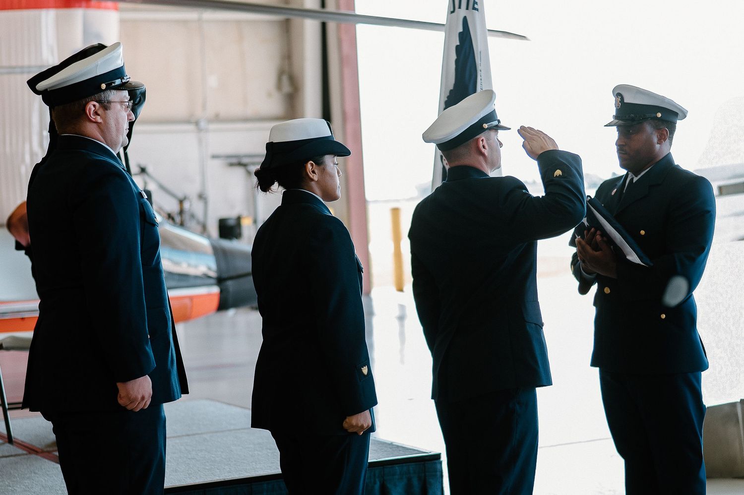 Military service members stand in formal dress uniforms during a ceremony.
