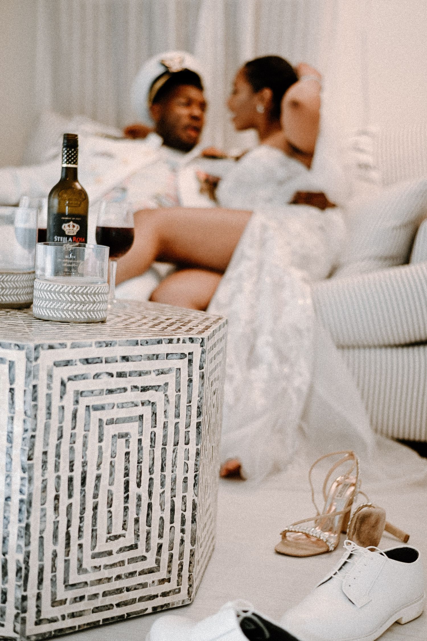 Elegant white lounge setting with decorative table and bottles for a wedding reception.