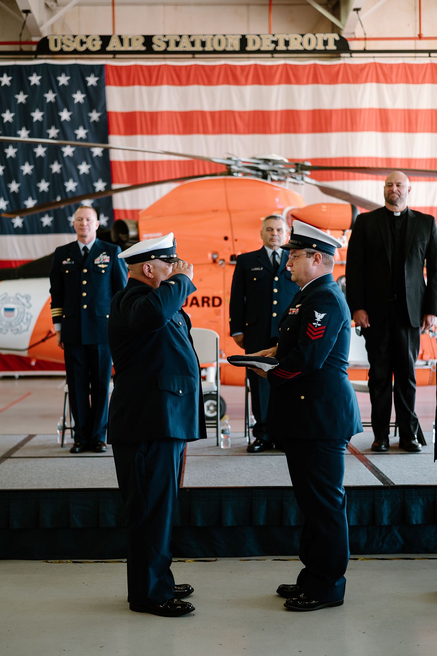 Coast Guard service members in dress uniforms conduct a ceremonial exchange.