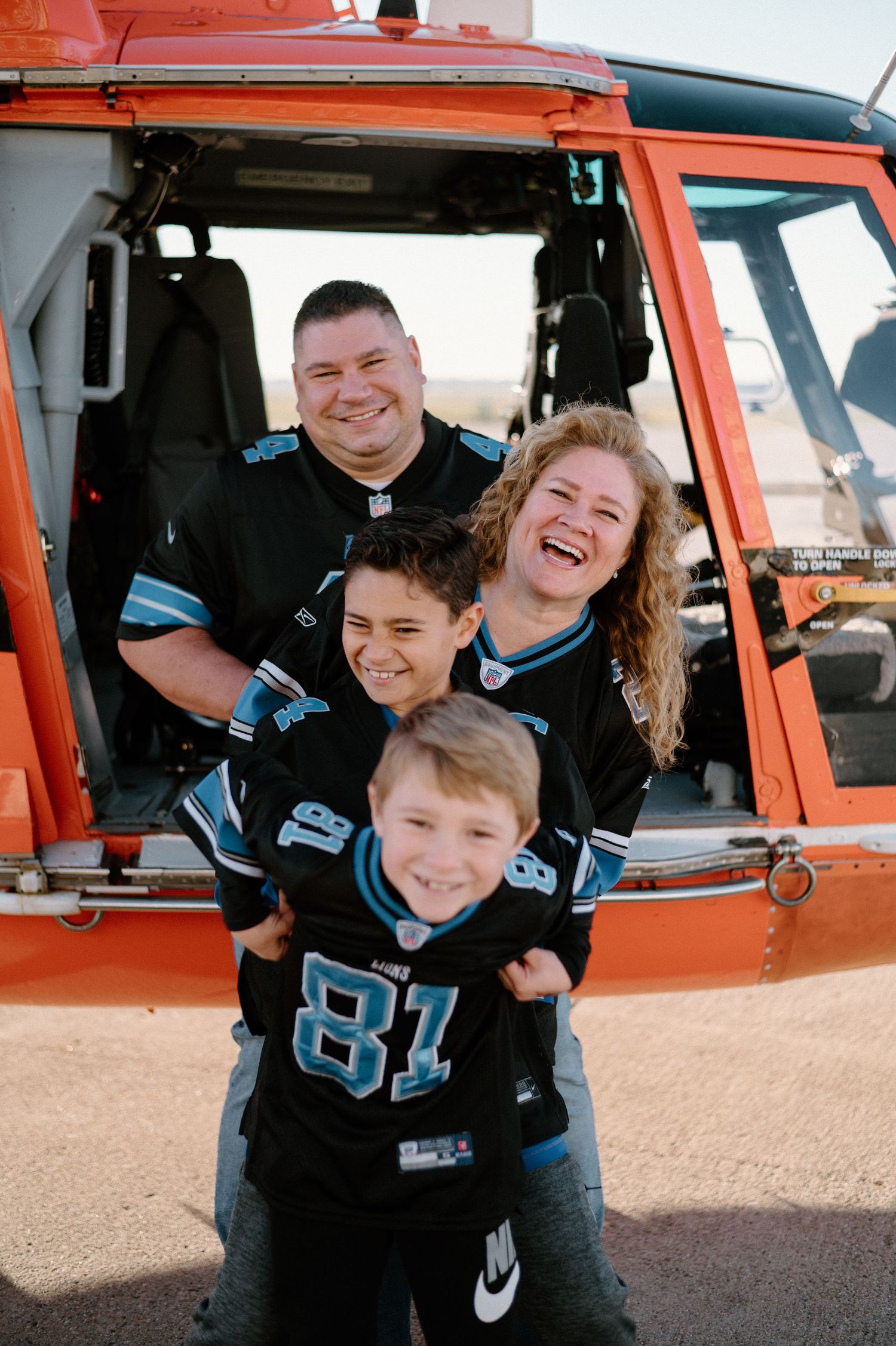 Group wearing matching blue jerseys share laughs inside orange helicopter.