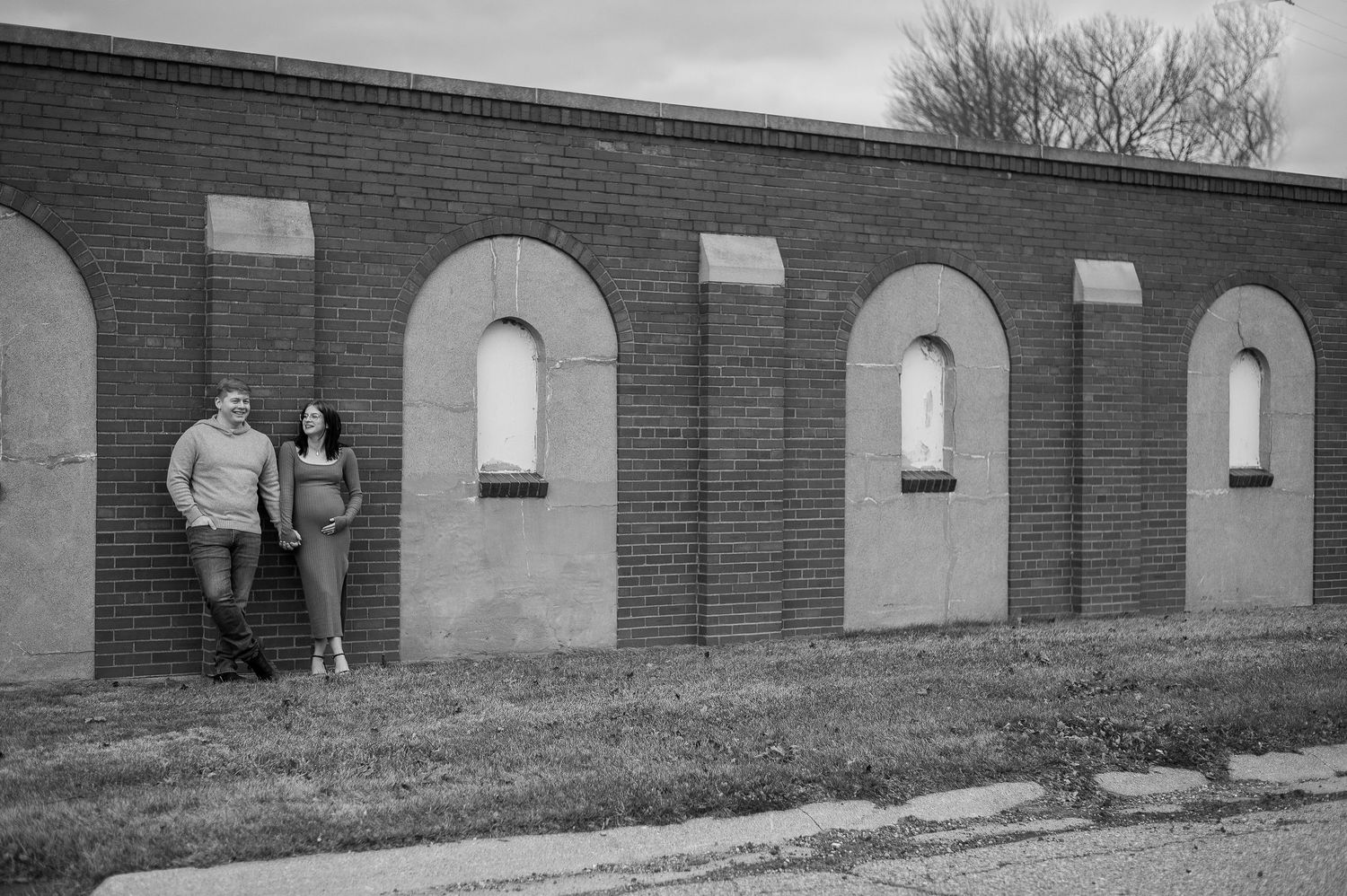 Long brick wall with repeating arched windows creates architectural backdrop for photos.