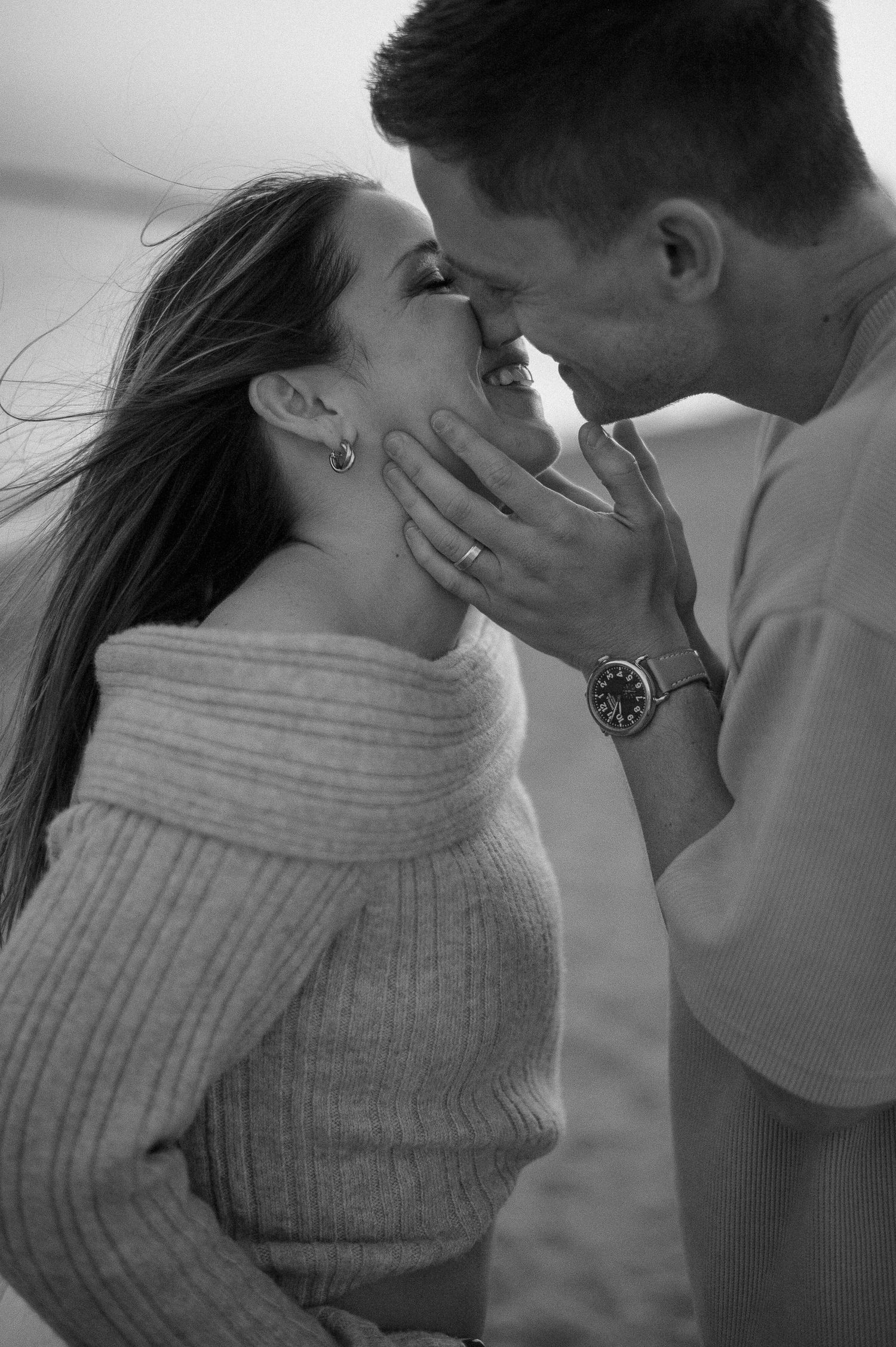 Romantic couple sharing an intimate moment in soft black and white lighting.