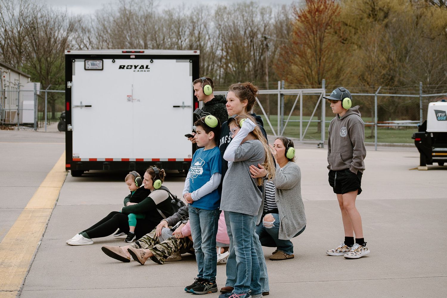 A group of people standing near a white utility trailer in a parking lot.