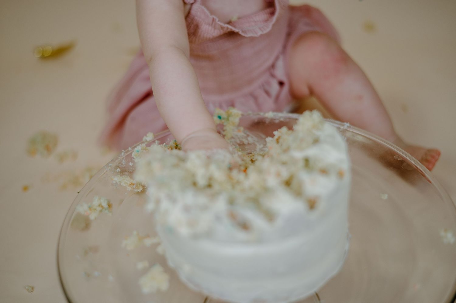 Baby hands reaching for and playing with white frosting or cream.
