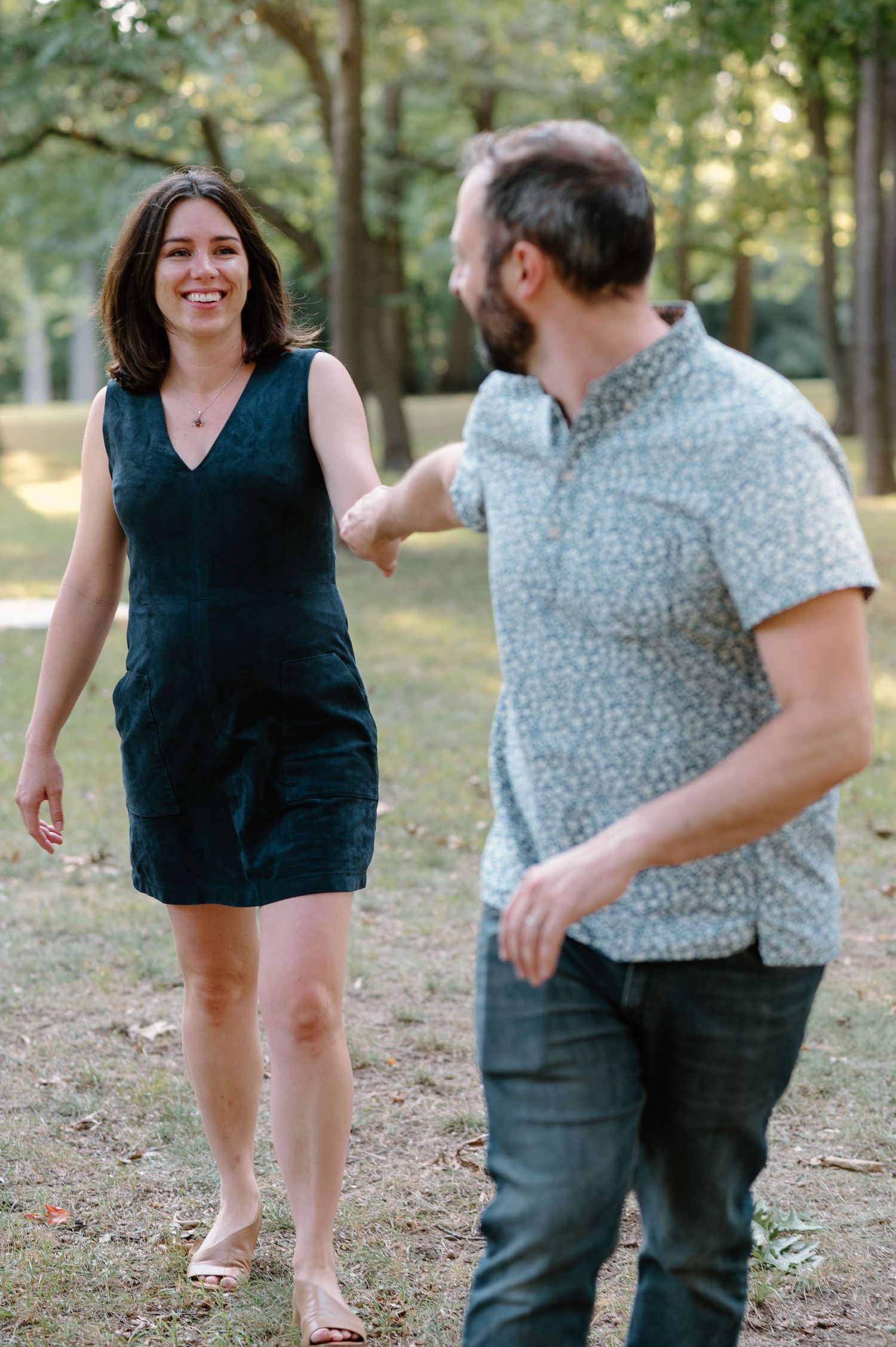Couple laughing and playing together in a wooded outdoor setting.