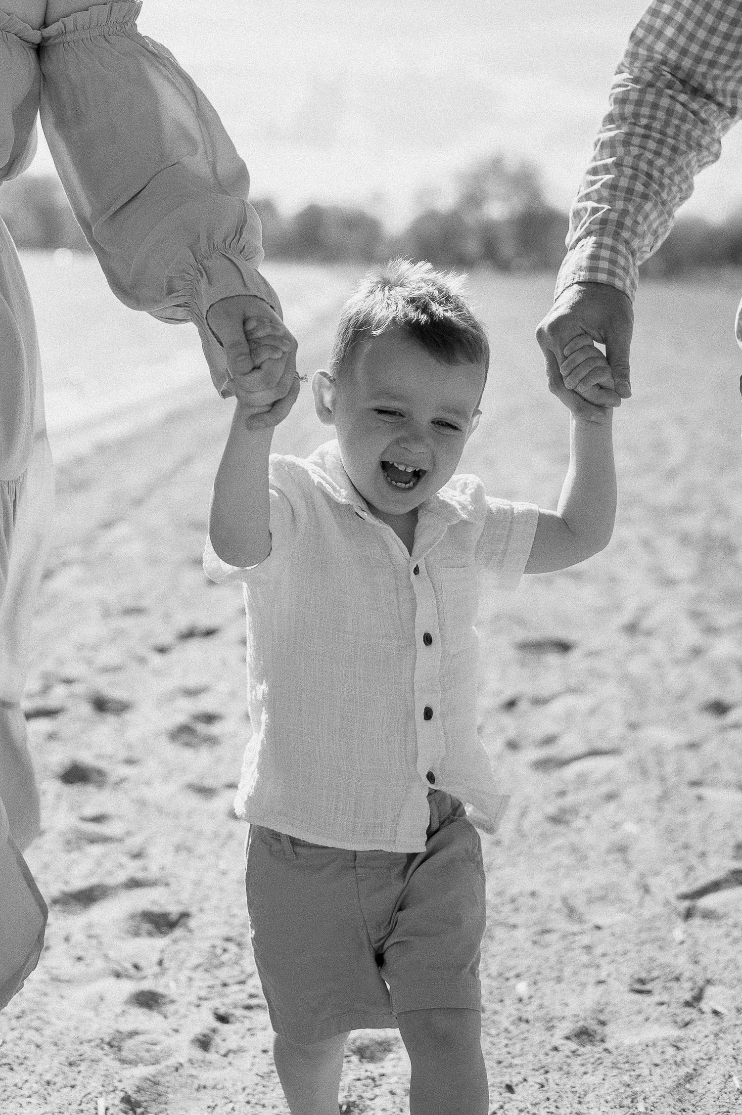 A sequence of playful moments on a sandy shore shown in black and white.
