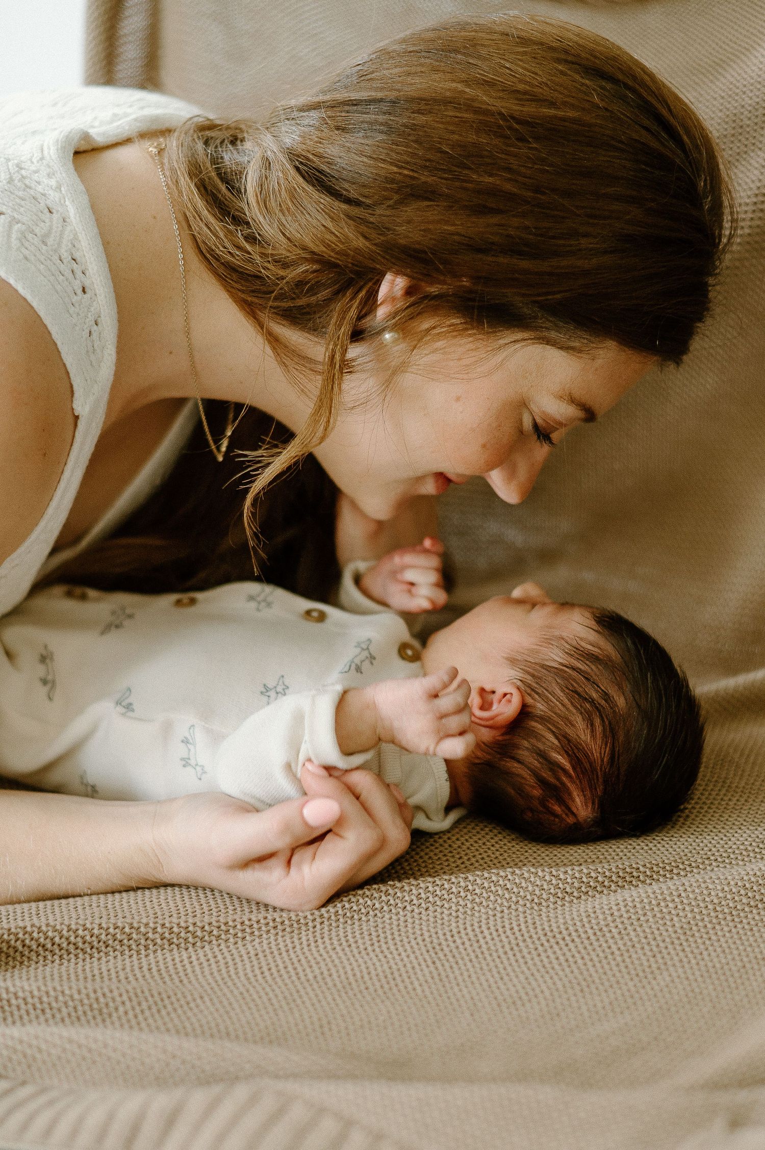 A tender moment shared with a newborn baby on a soft beige surface.