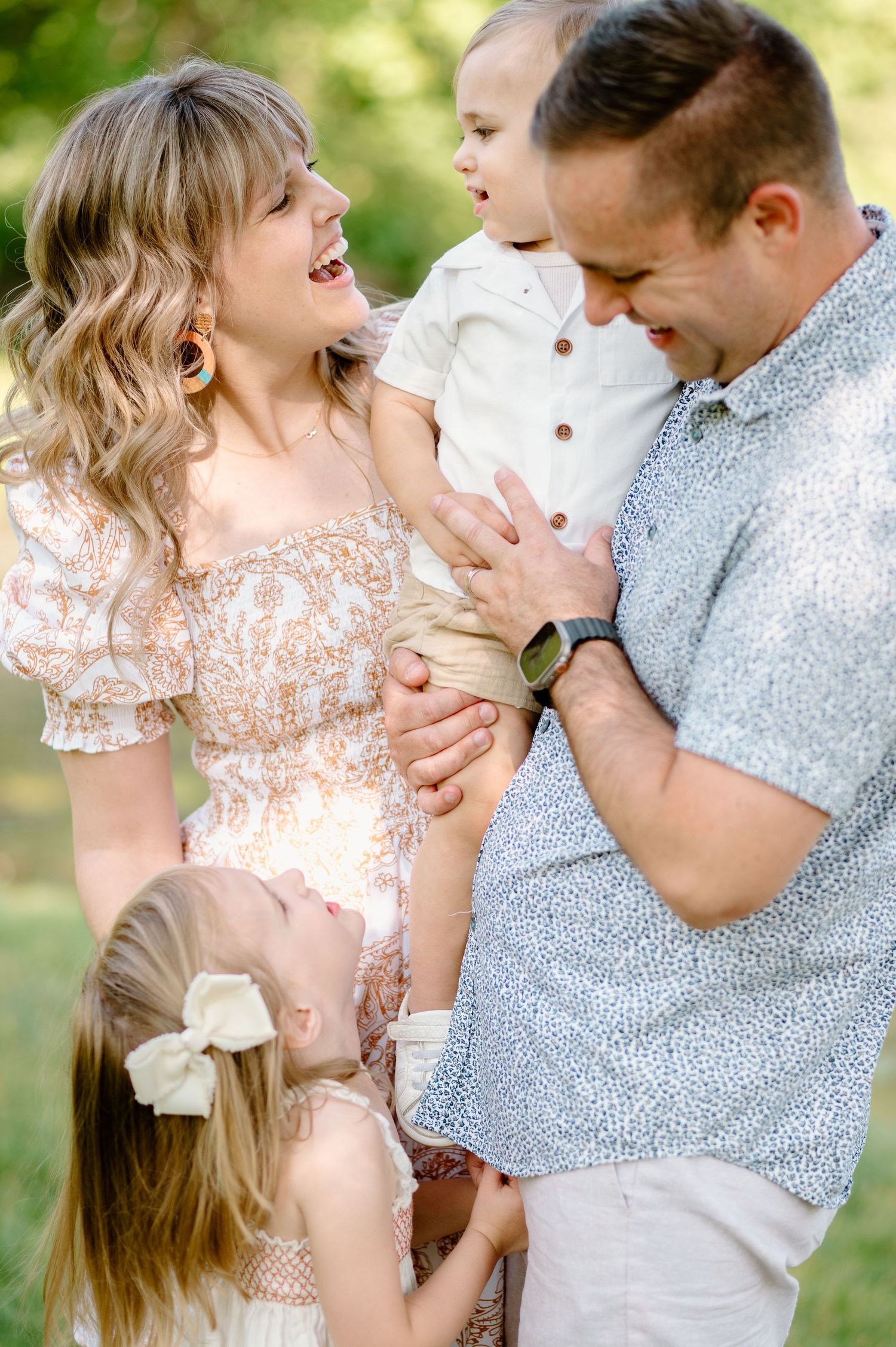 Romantic couple sharing intimate laughing moments in sunlit outdoor setting.