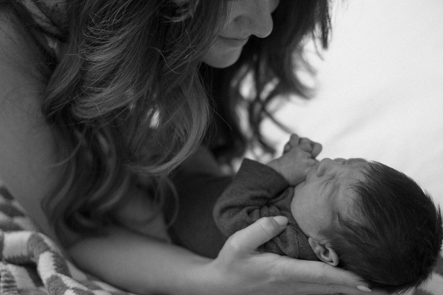 Close-up tender moment between parent and newborn in black and white.