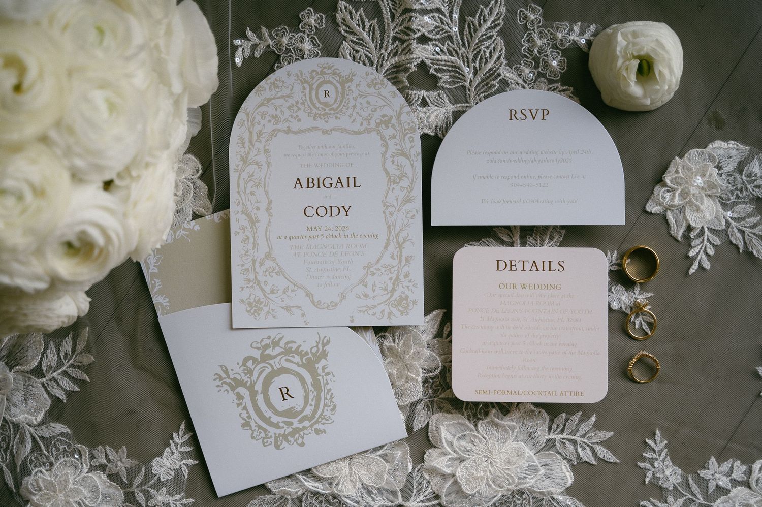 Elegant wedding invitation suite featuring arched cards for Abigail and Cody, RSVP, and details cards on lace fabric.