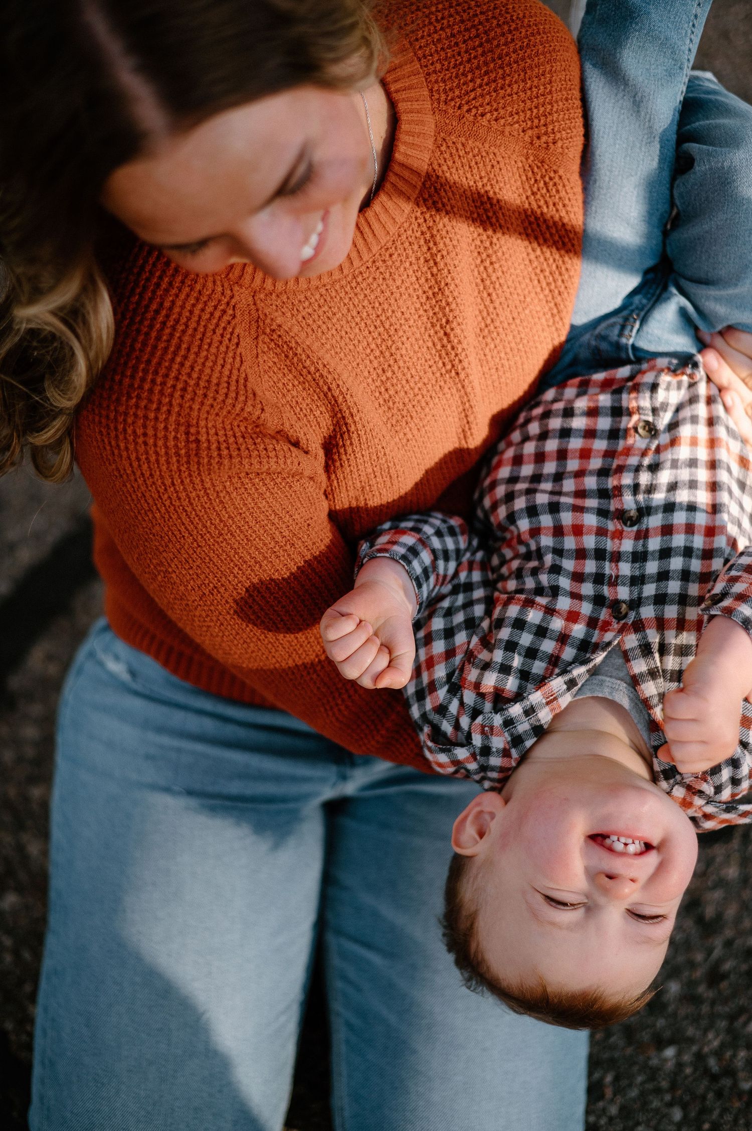 Joyful parent holding child upside down during playful moment.
