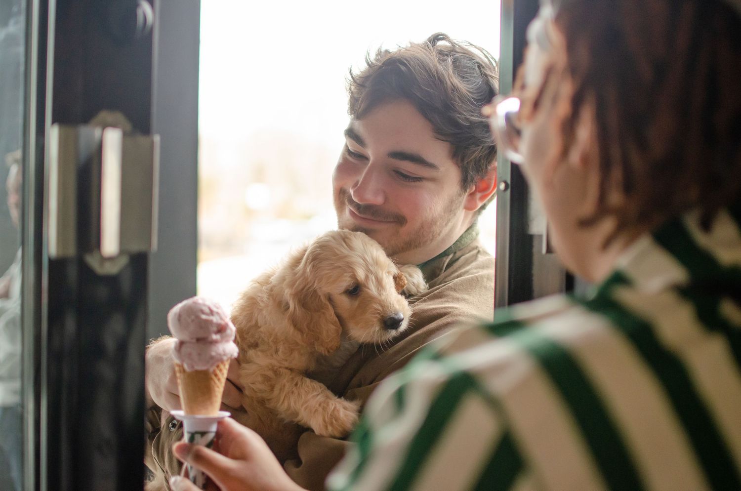 Two friends enjoying ice cream cones together at a cafe while laughing and having a social moment.