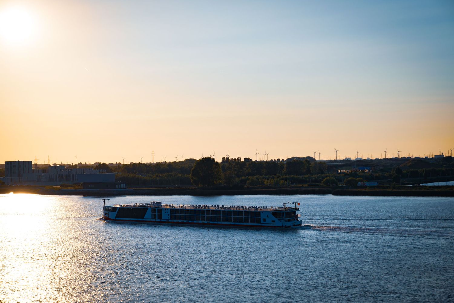 Prachtige zonsondergang over de Antwerpse rivier met een vrachtschip, gefotografeerd door Roger met warme belichting.