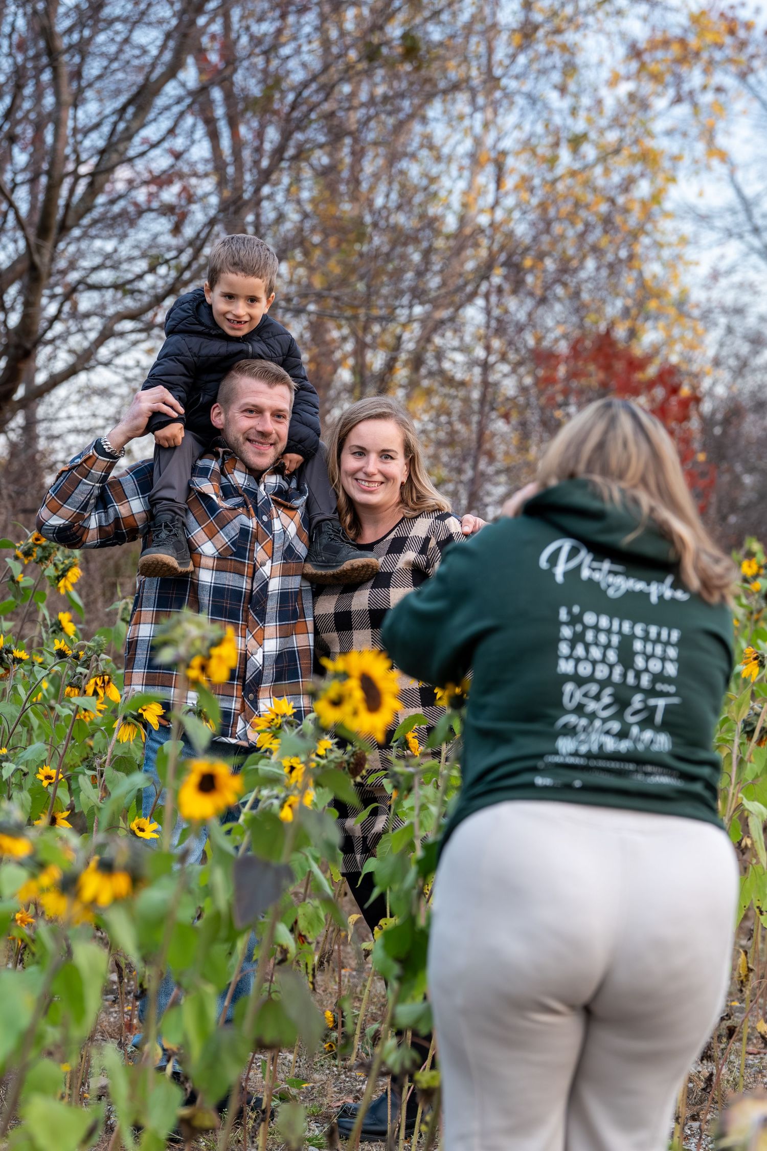 Photography session in a field with yellow wildflowers and fall trees.