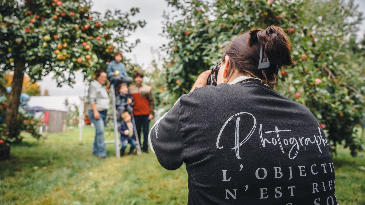 Photographers capturing moments at an outdoor event with apple trees in the background.