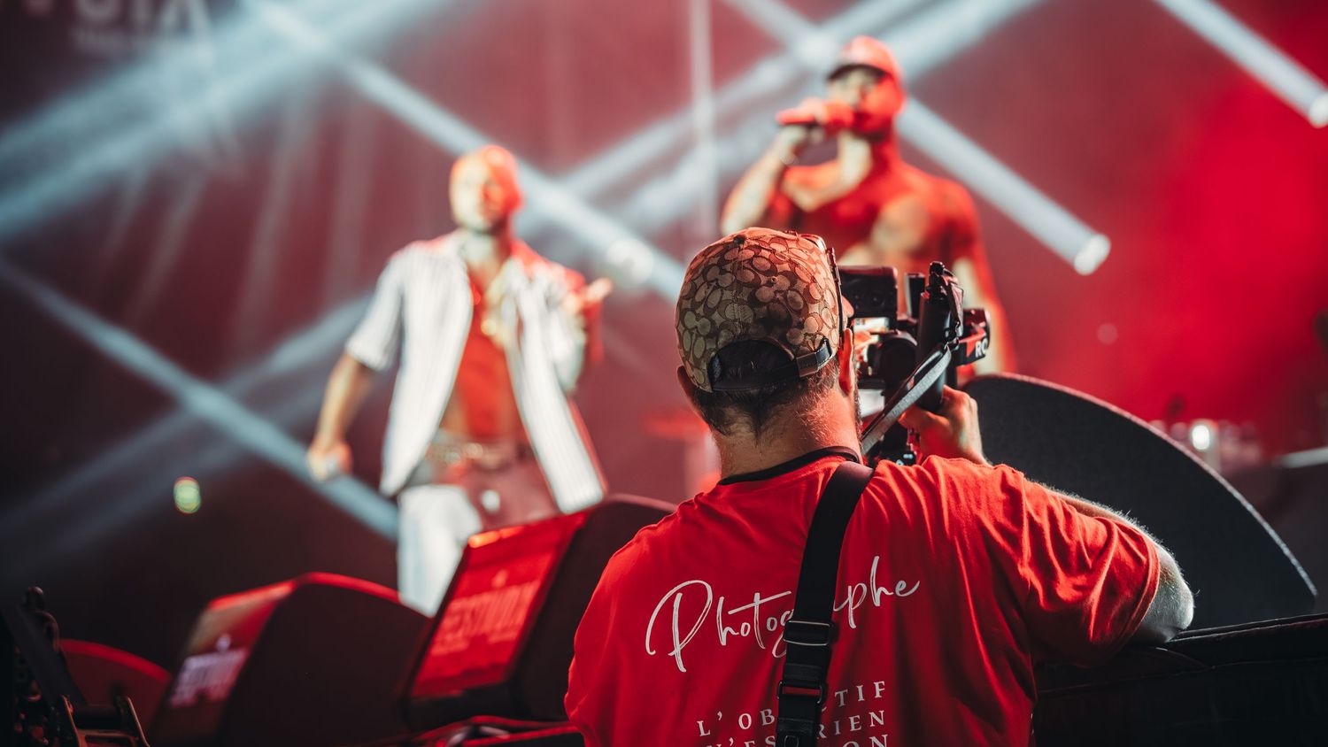Concert stage lighting with dramatic red beams creating atmospheric effects.
