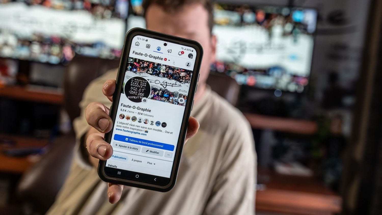 Hand holding smartphone displaying social media interface in dark room.