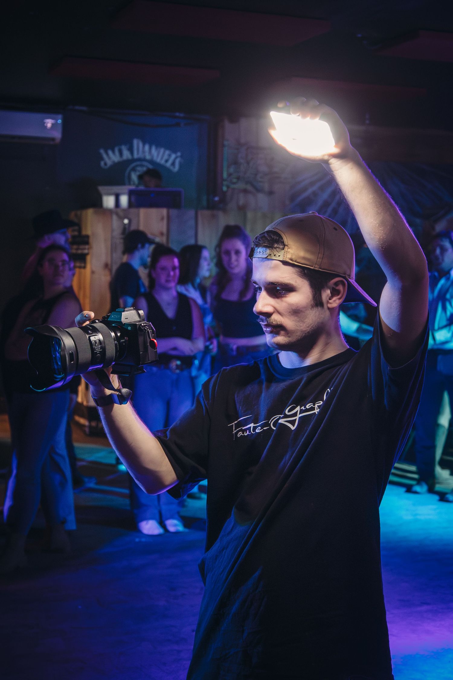 Photographer working at night event with blue lighting and Jack Daniels branding visible.