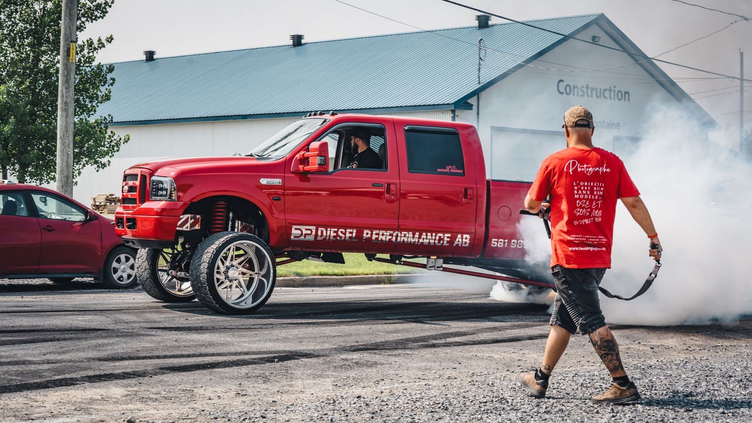 Red pickup truck creating smoke during a photography shoot.
