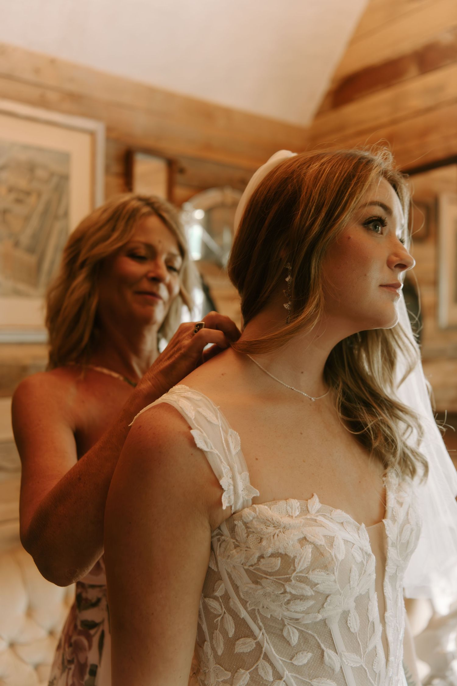Close-up details of an elegant white wedding dress bodice with delicate lace overlay in warm lighting.
