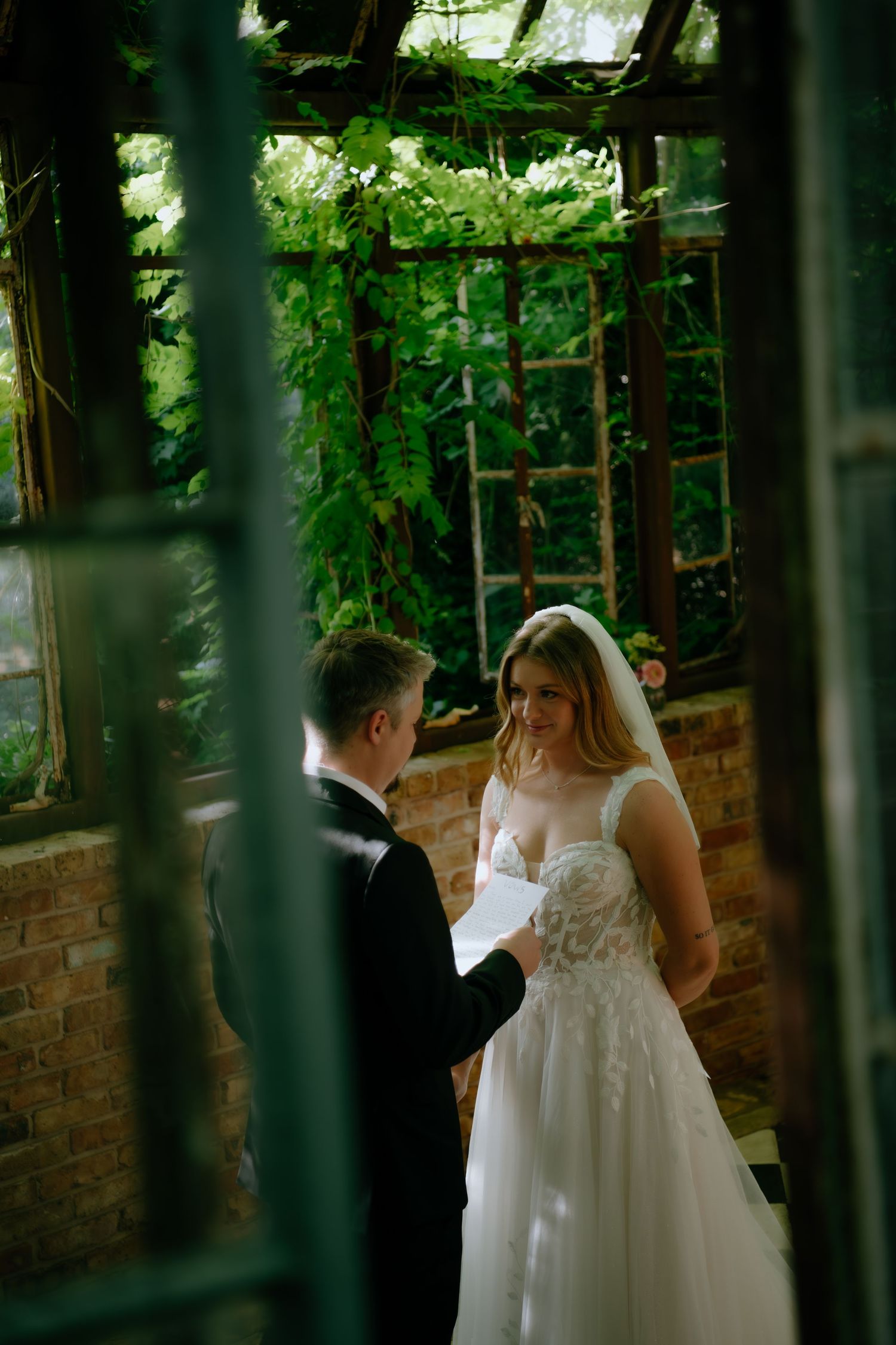 Wedding vows being exchanged in a greenhouse surrounded by climbing vines.