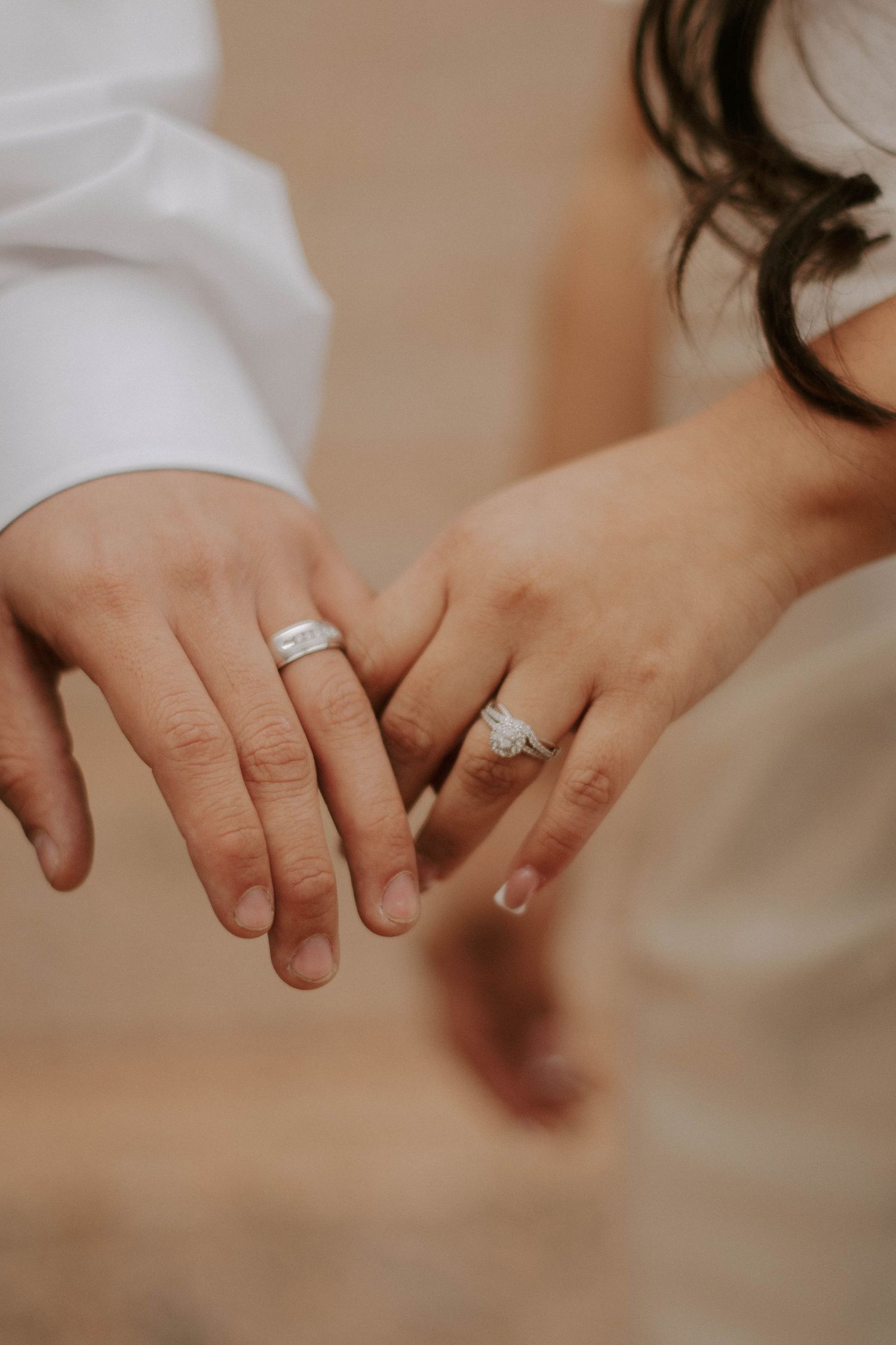 Close-up of newlyweds' hands displaying their wedding rings against a soft background.