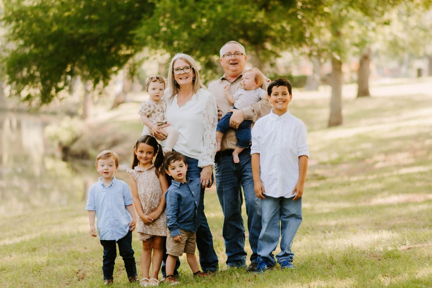 Group of people posing together on a grassy hillside for a casual outdoor photo.