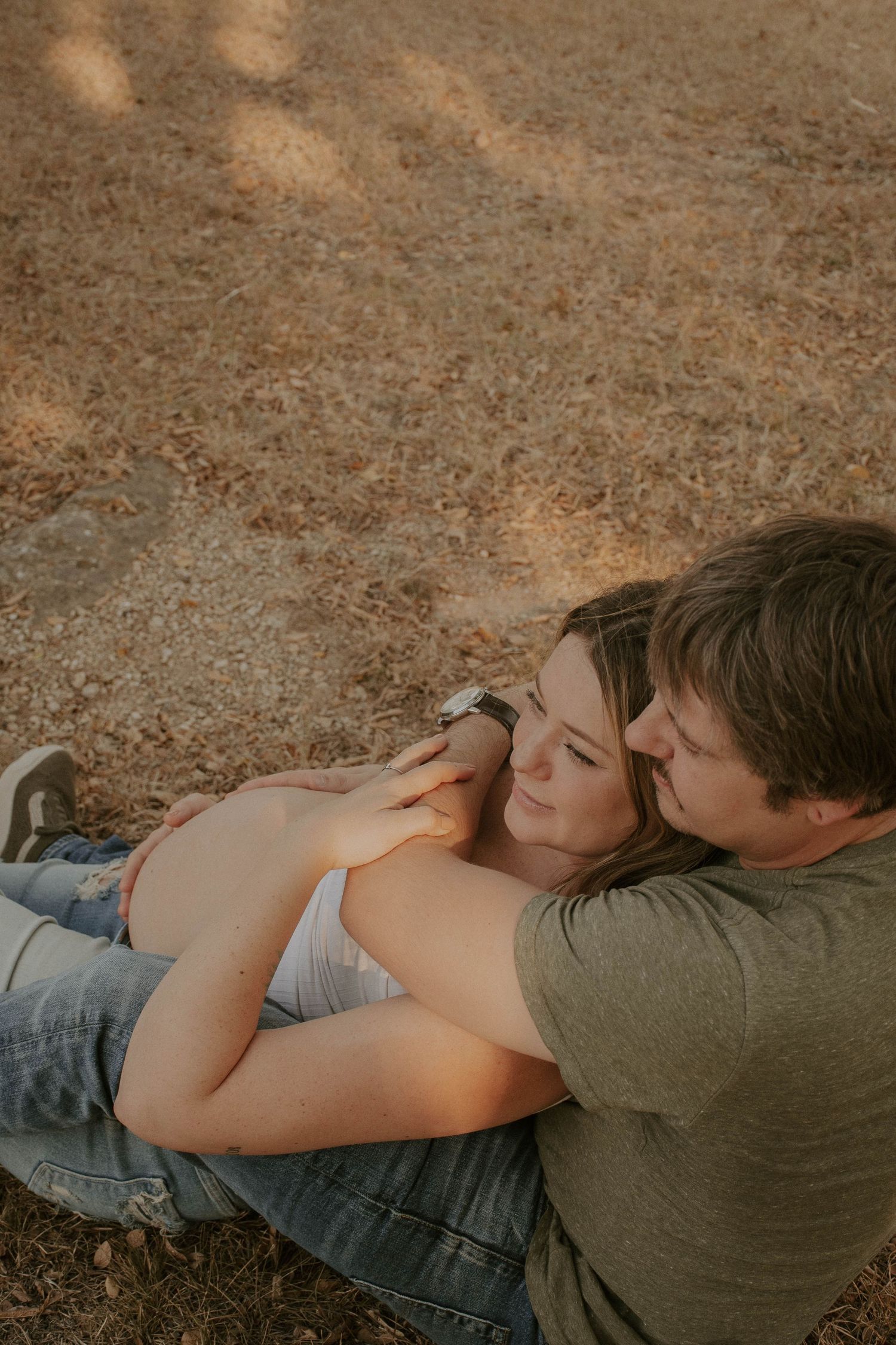 Couple lying together on rustic ground during golden hour.