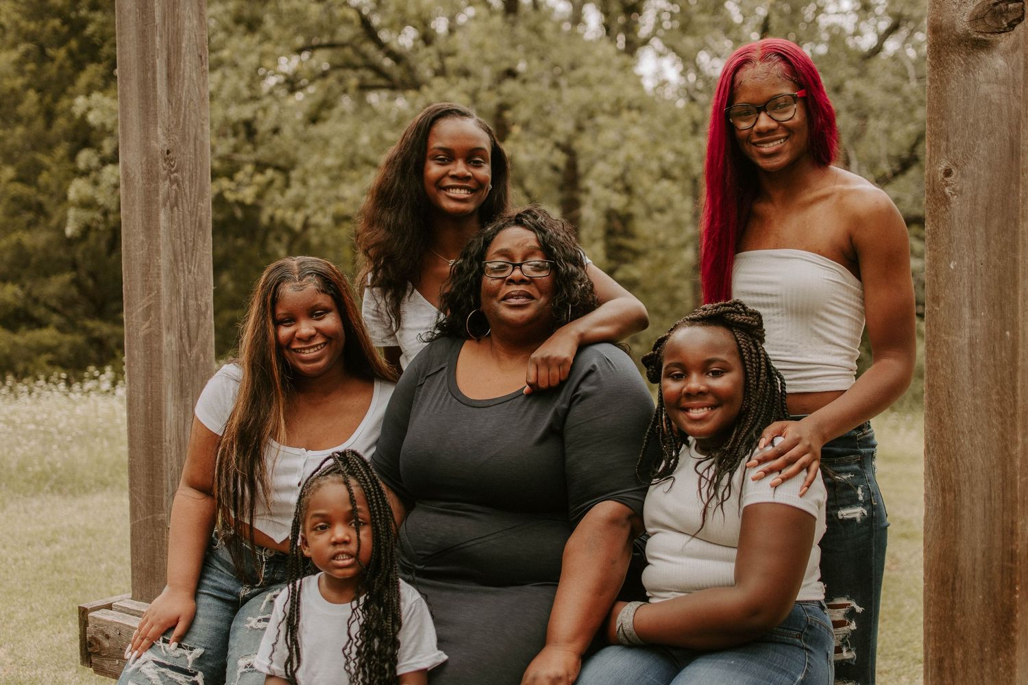 Extended family posing together for portraits outdoors near wooden posts.