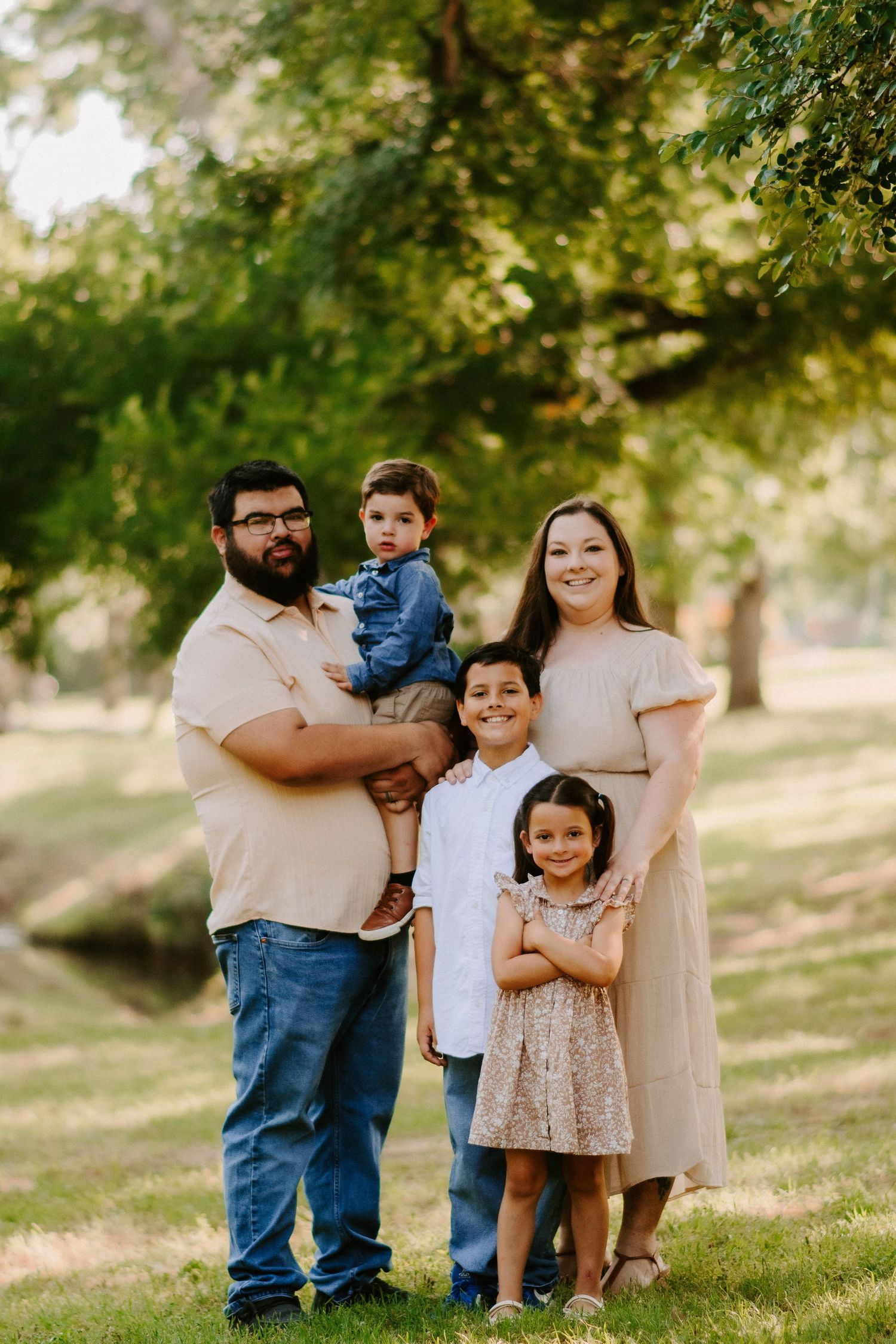 A cheerful family poses together in a park setting during golden hour.