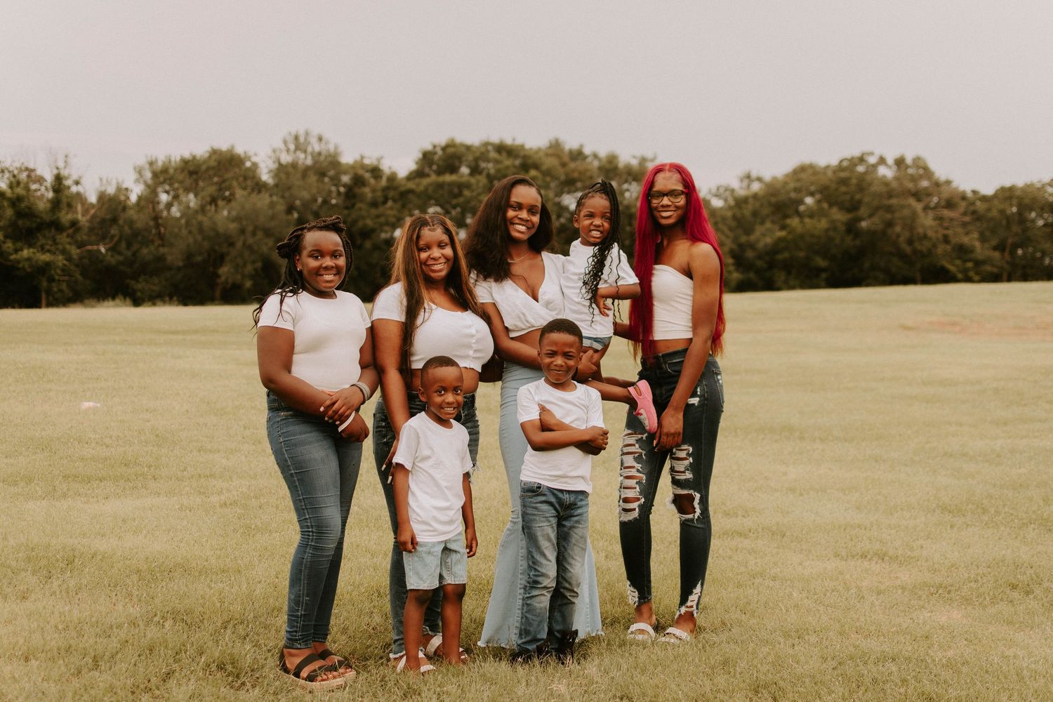 Extended family group photo in casual attire standing together in an open field.