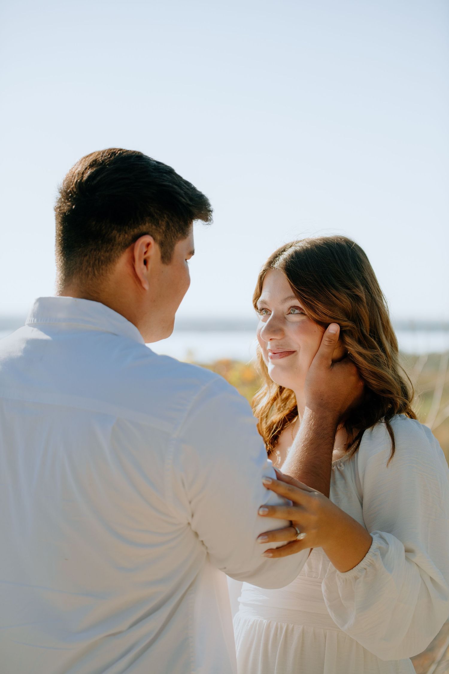 A romantic couple in white clothing share tender moments in a series of intimate photographs outdoors.