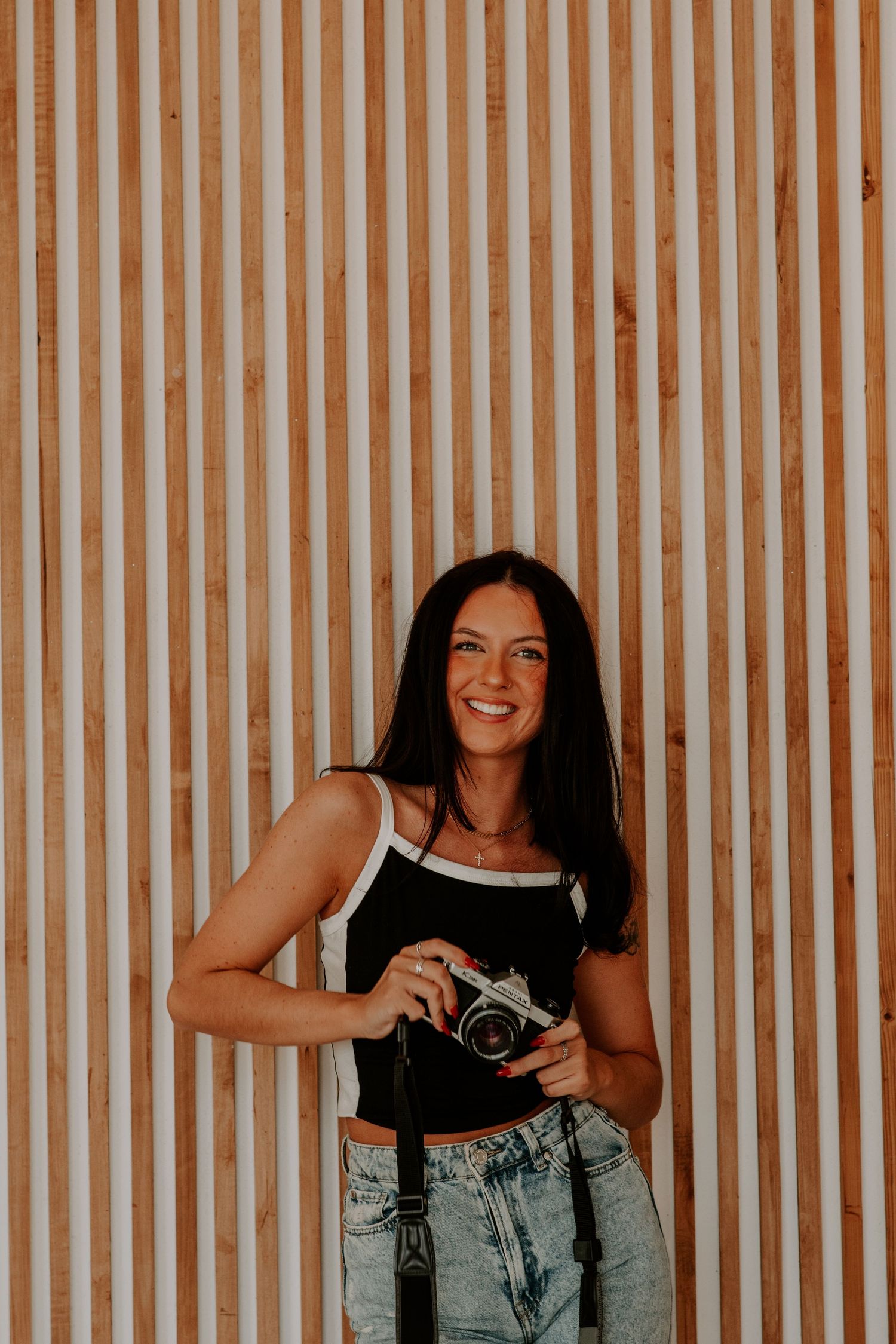 Portrait against striped wooden wall background with vintage camera.