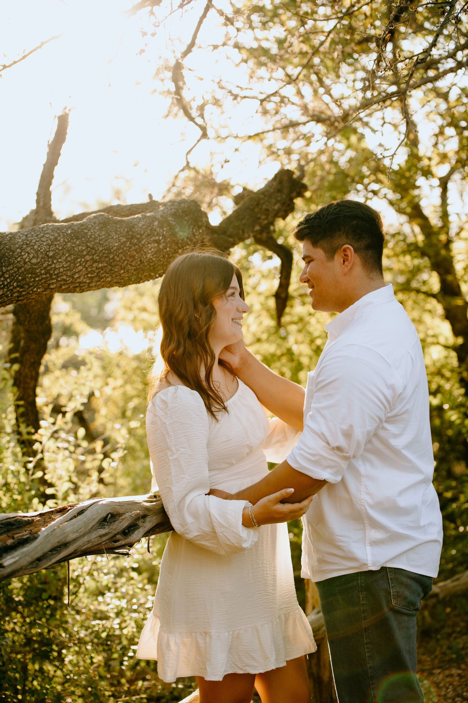 Two people share a romantic dance among trees with sunlight filtering through branches.