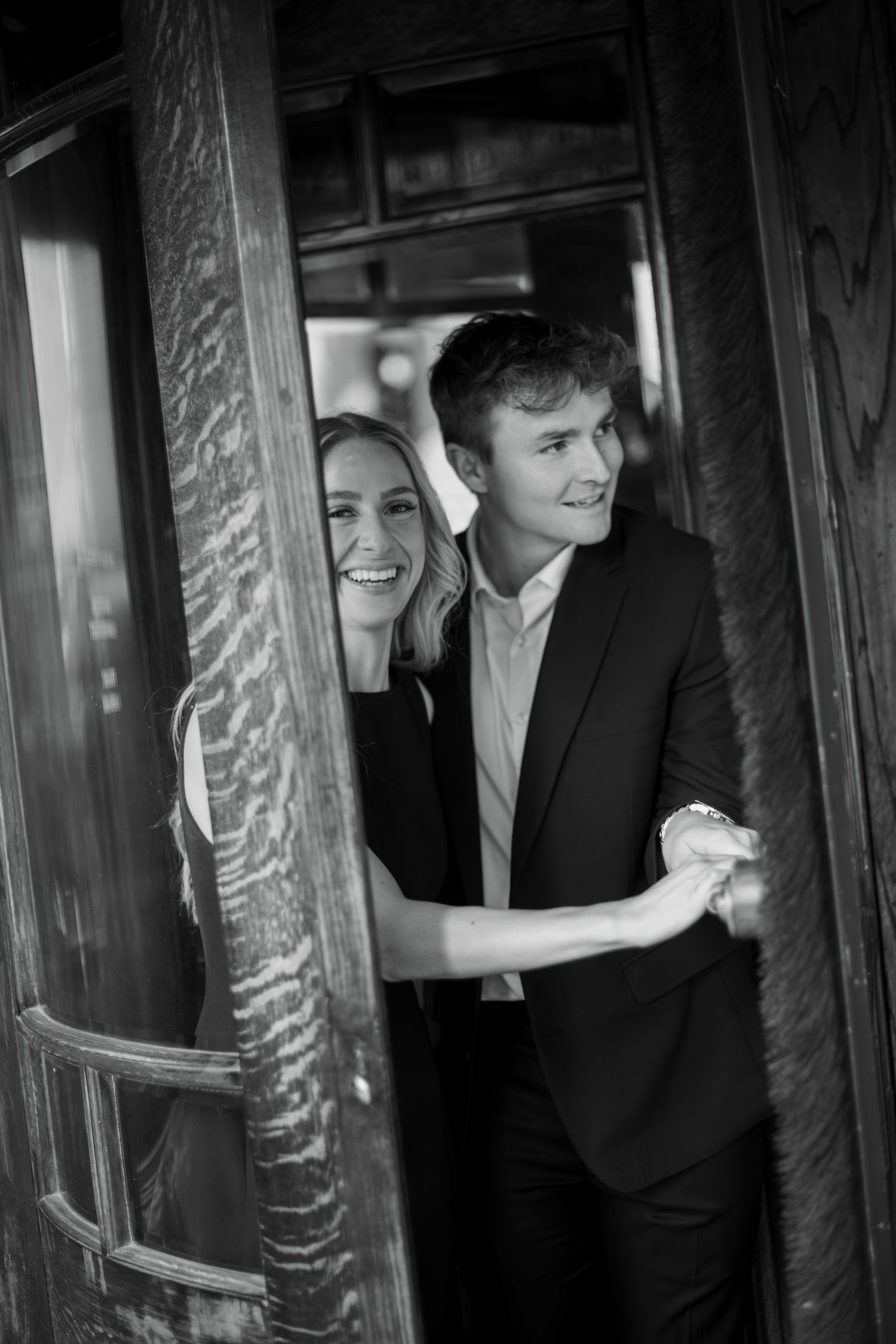 A black and white photo series showing people in formal attire posing inside what appears to be a phone booth.