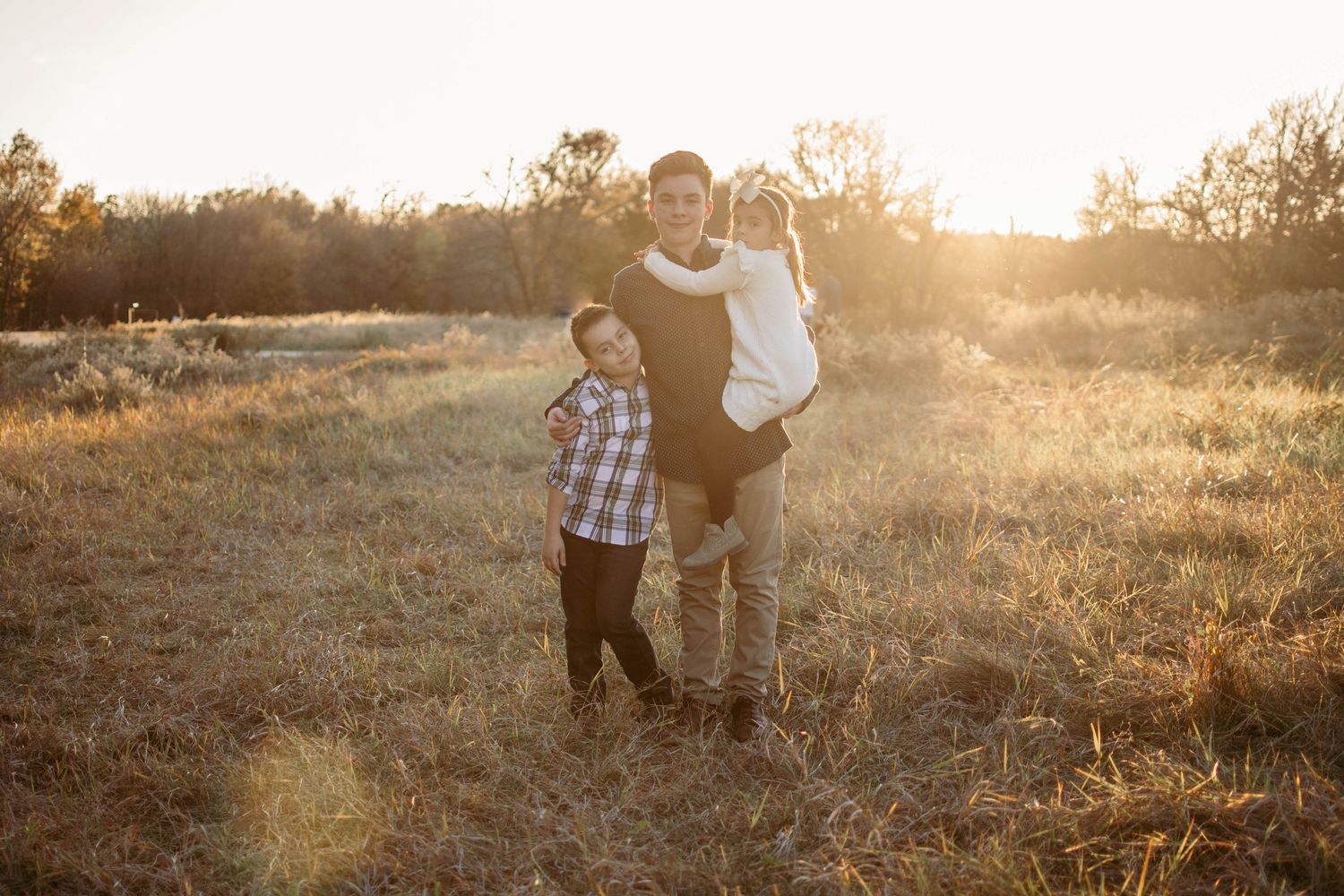 Silhouetted figures in a golden field during sunset with warm backlighting.