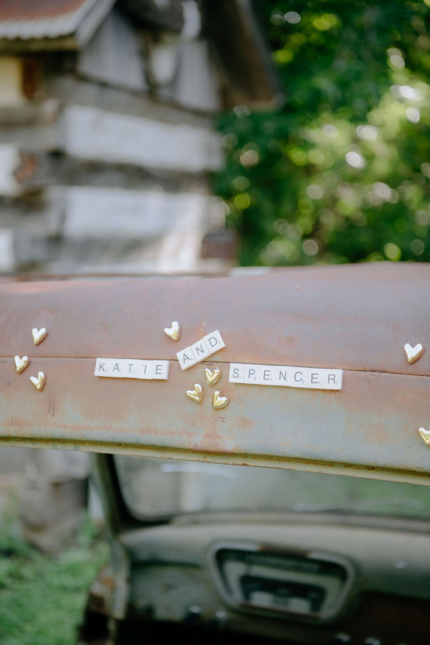Names Katie and Spencer displayed with small paper hearts on a rustic surface.