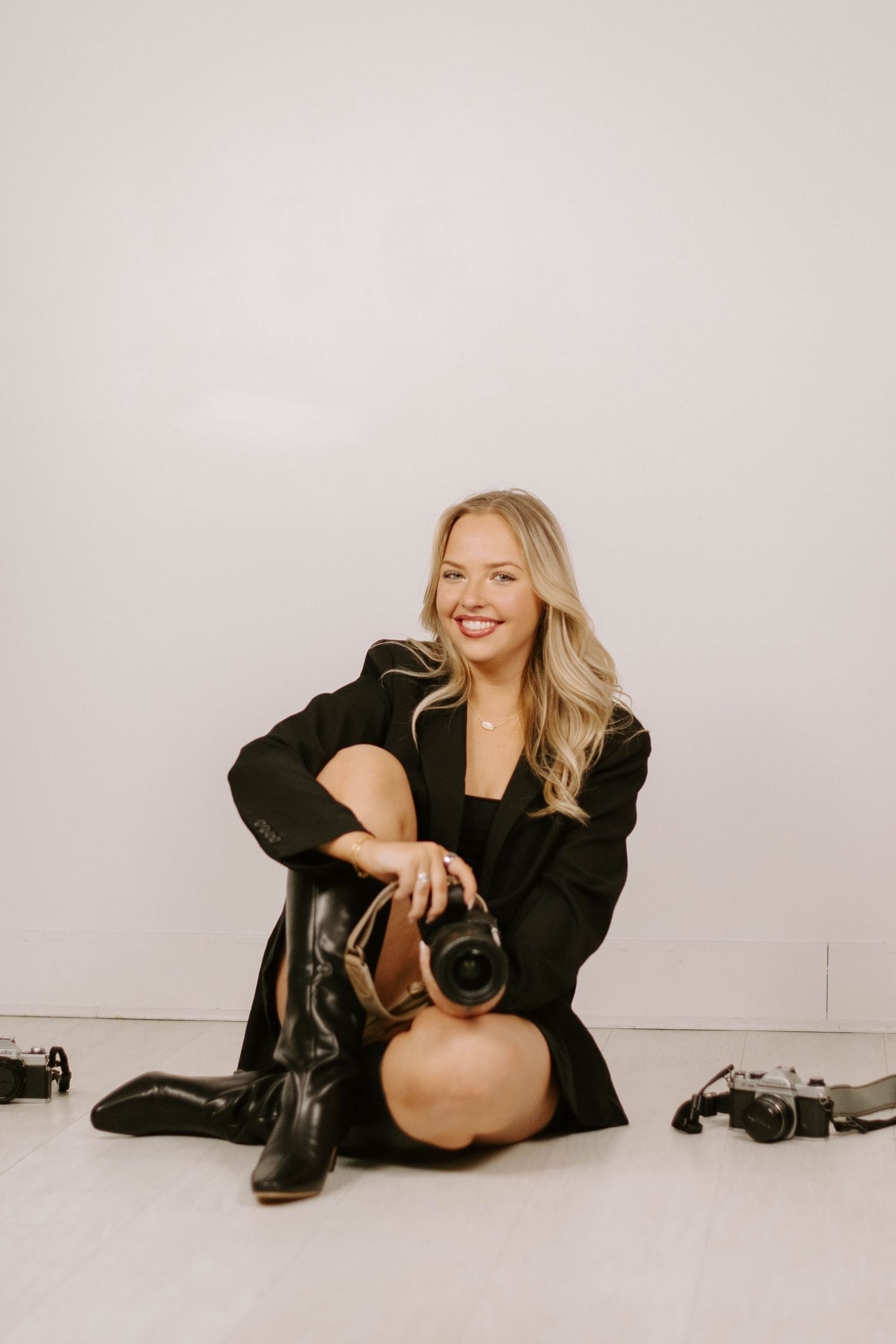 A series of artistic black and white studio photos showing a person in a black blazer lounging on the floor.