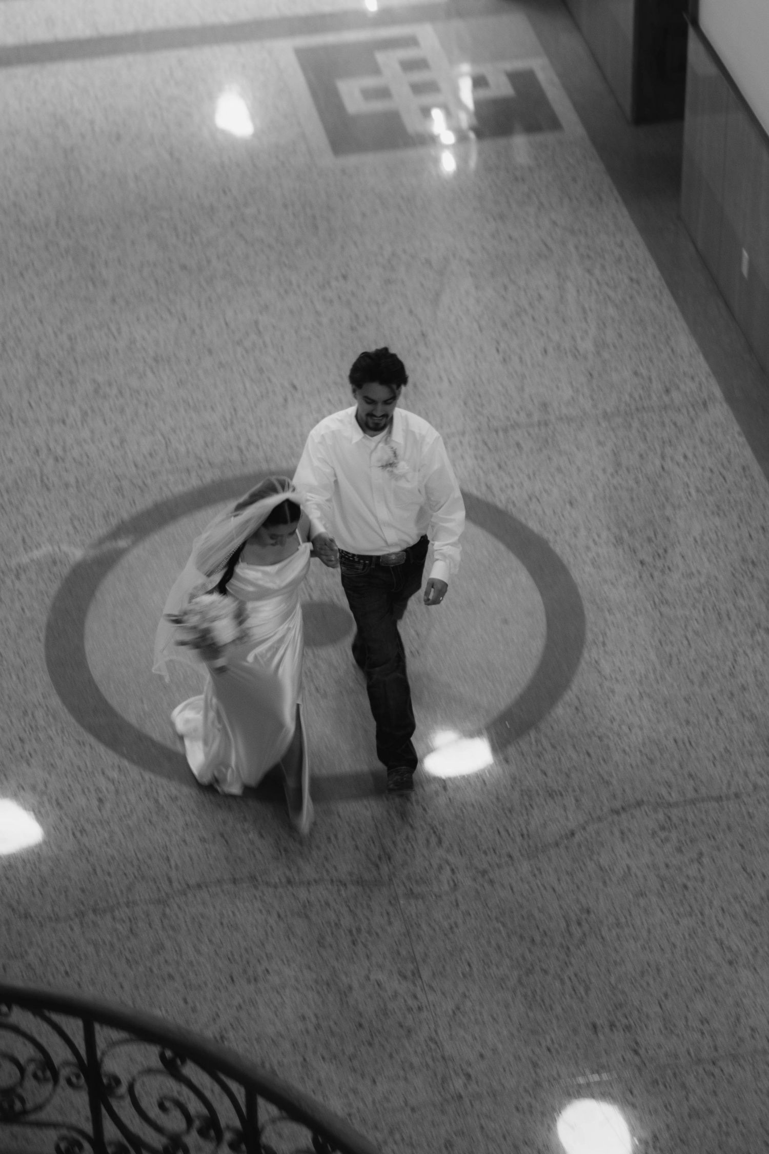 Overhead view of couple walking across circular pattern on marble floor.