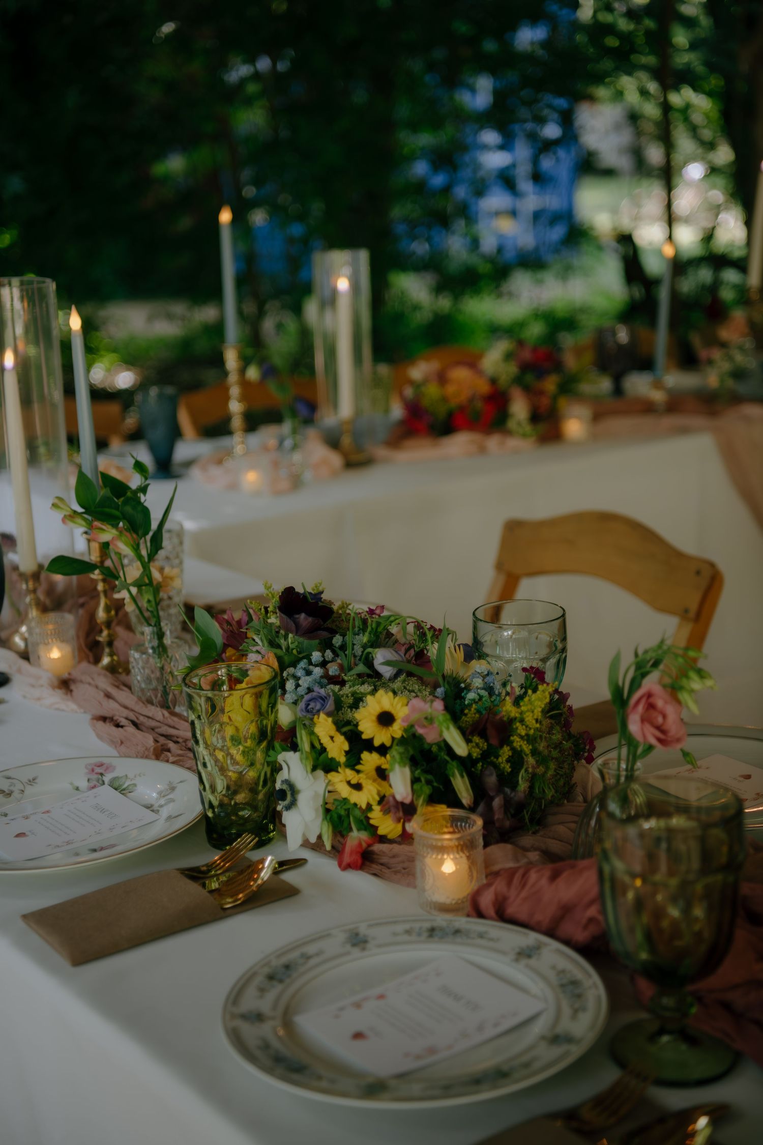 Wedding reception table decorated with wildflower arrangements, candles and vintage place settings.