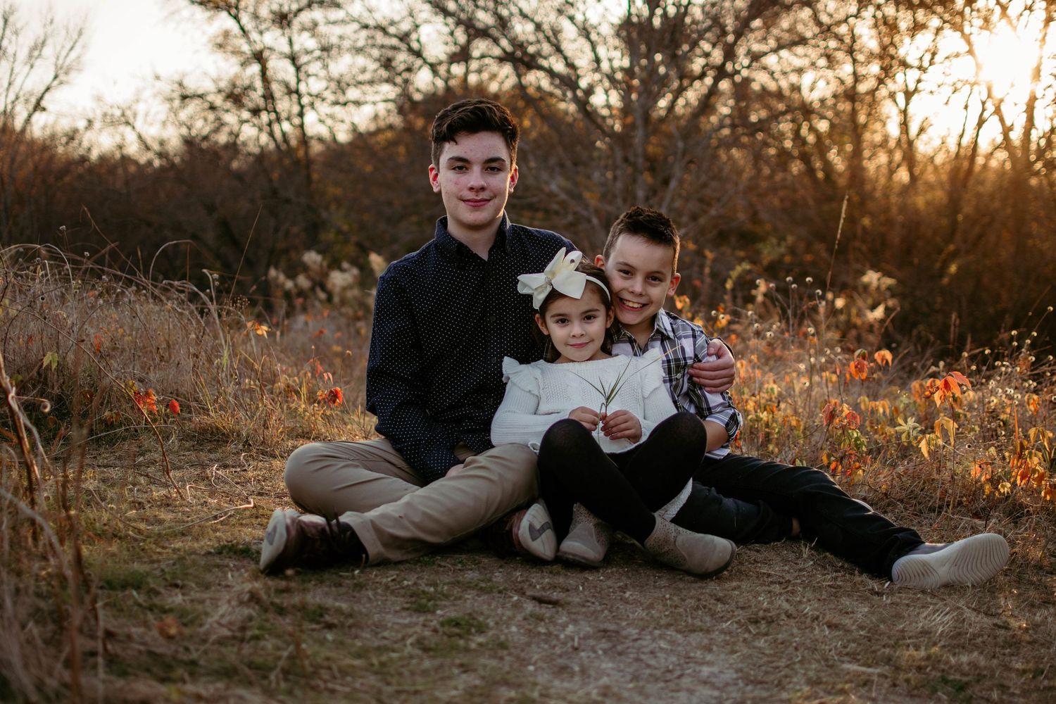 Casual family portrait with relaxed poses in autumnal setting during golden hour.
