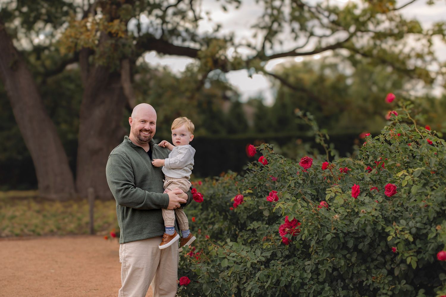 Family spending time together in a garden with red roses and autumn trees.