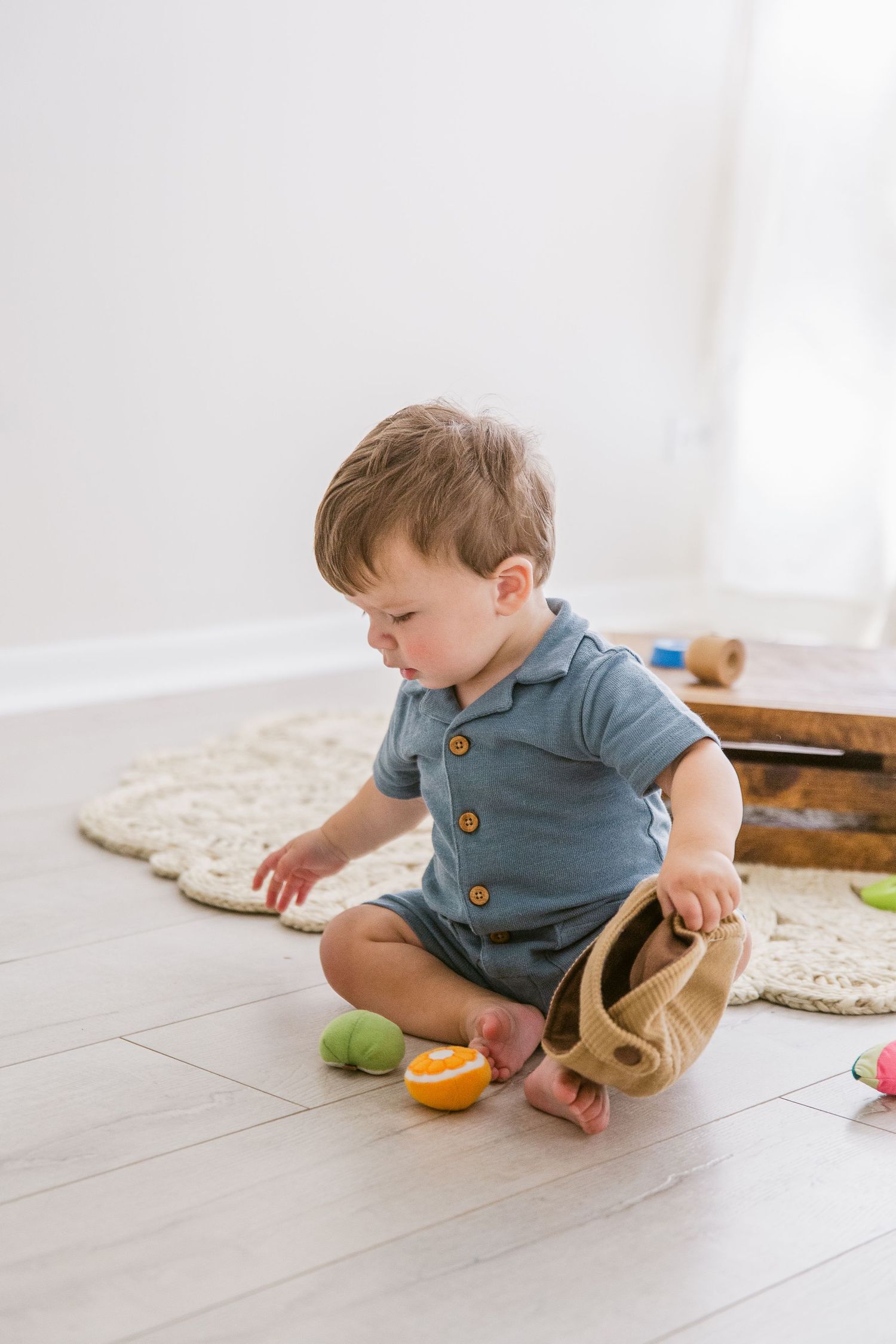 Small child playing with toys on patterned rug in minimalist room setting.