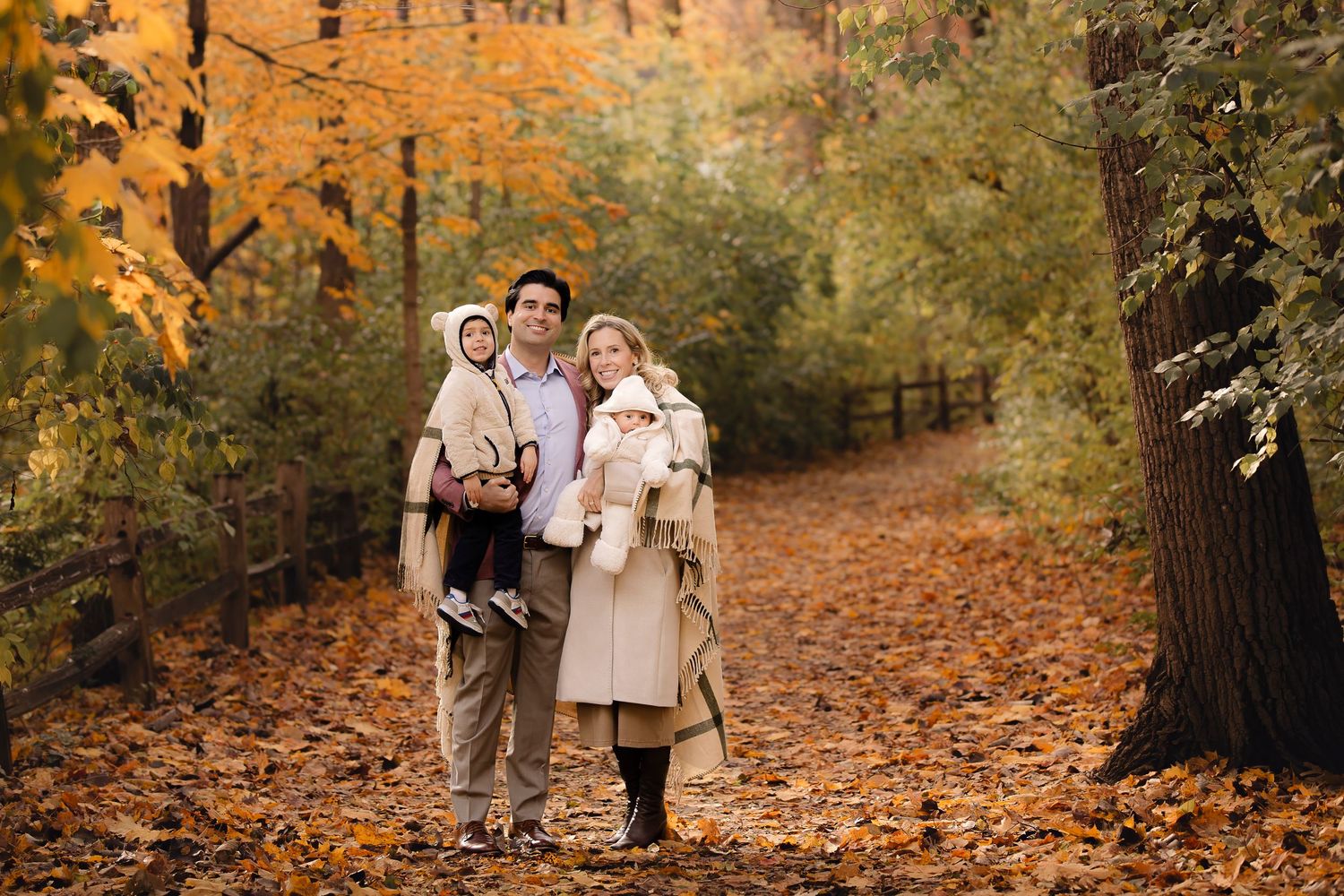 Couple walking together on a leaf-covered path through vibrant autumn forest during golden hour.