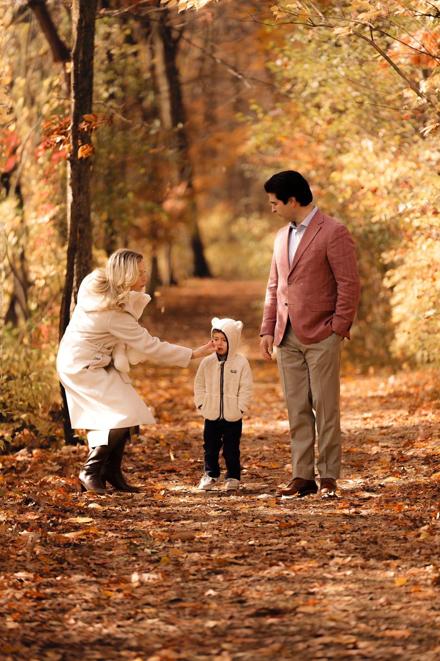 Four sequential photos show a couple walking and playing in autumn leaves along a wooded path.