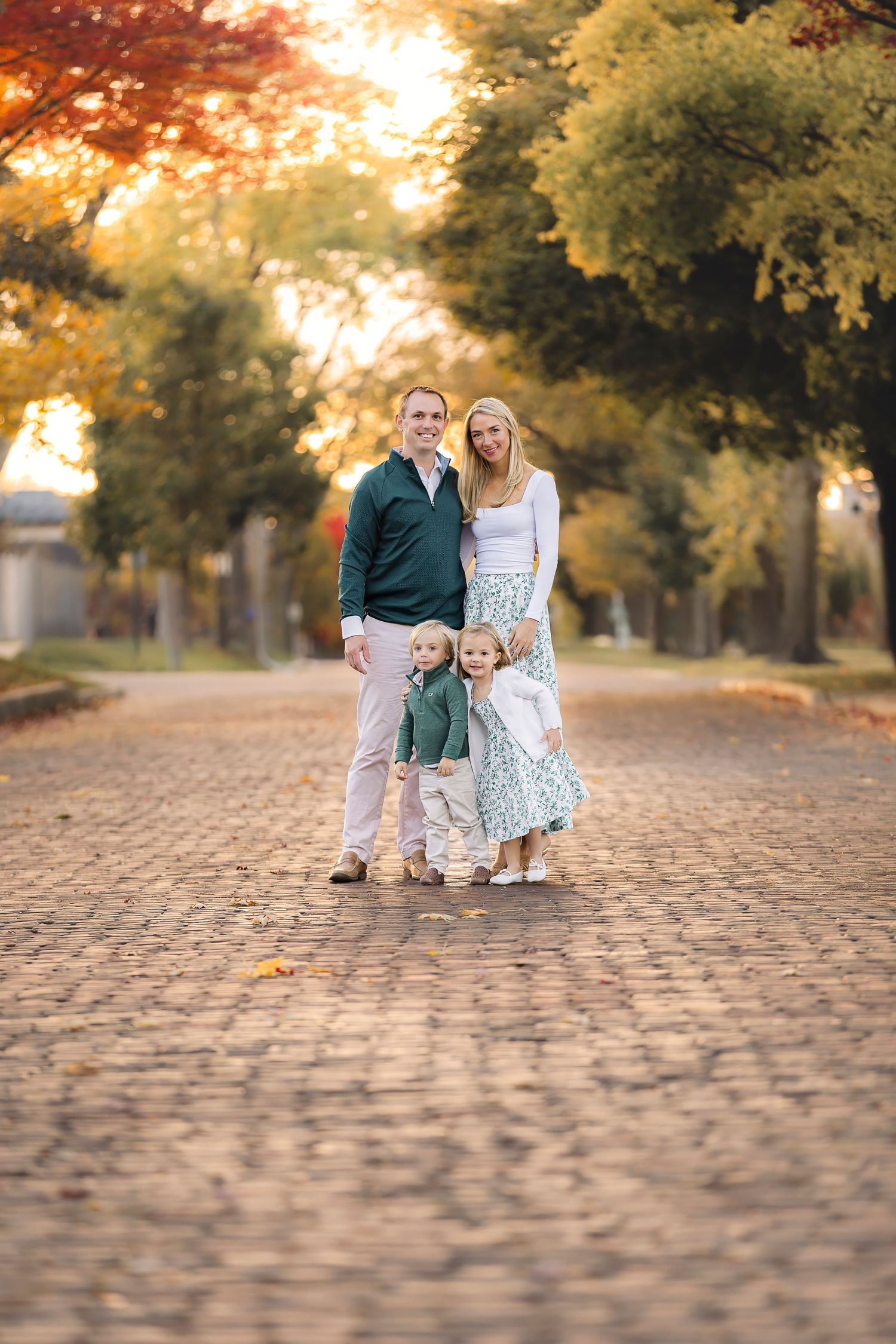 Young couple walking together on cobblestone path during golden sunset in autumn park.