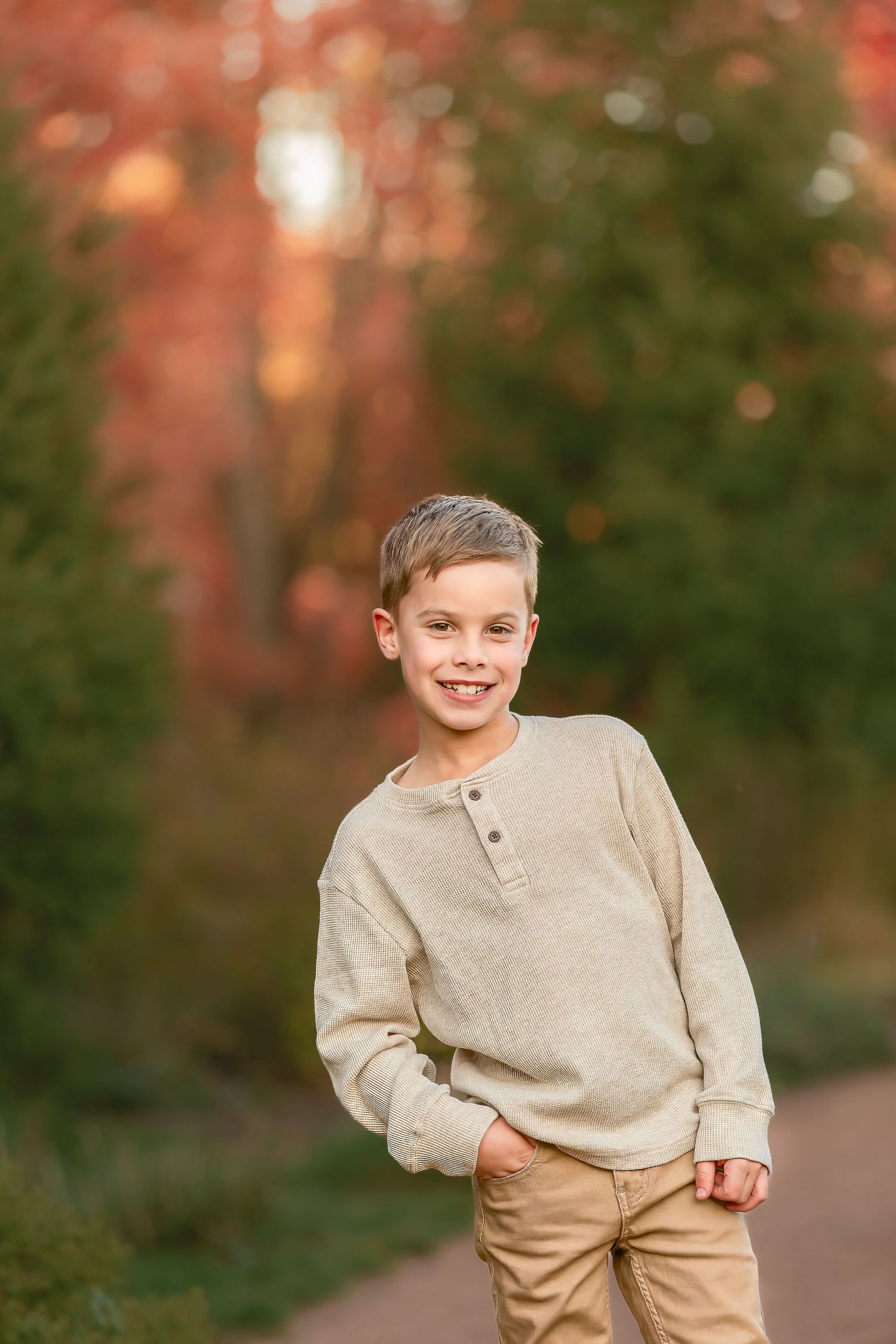 A series of five outdoor portrait photos showing playful expressions in a beige sweater against an autumn background.