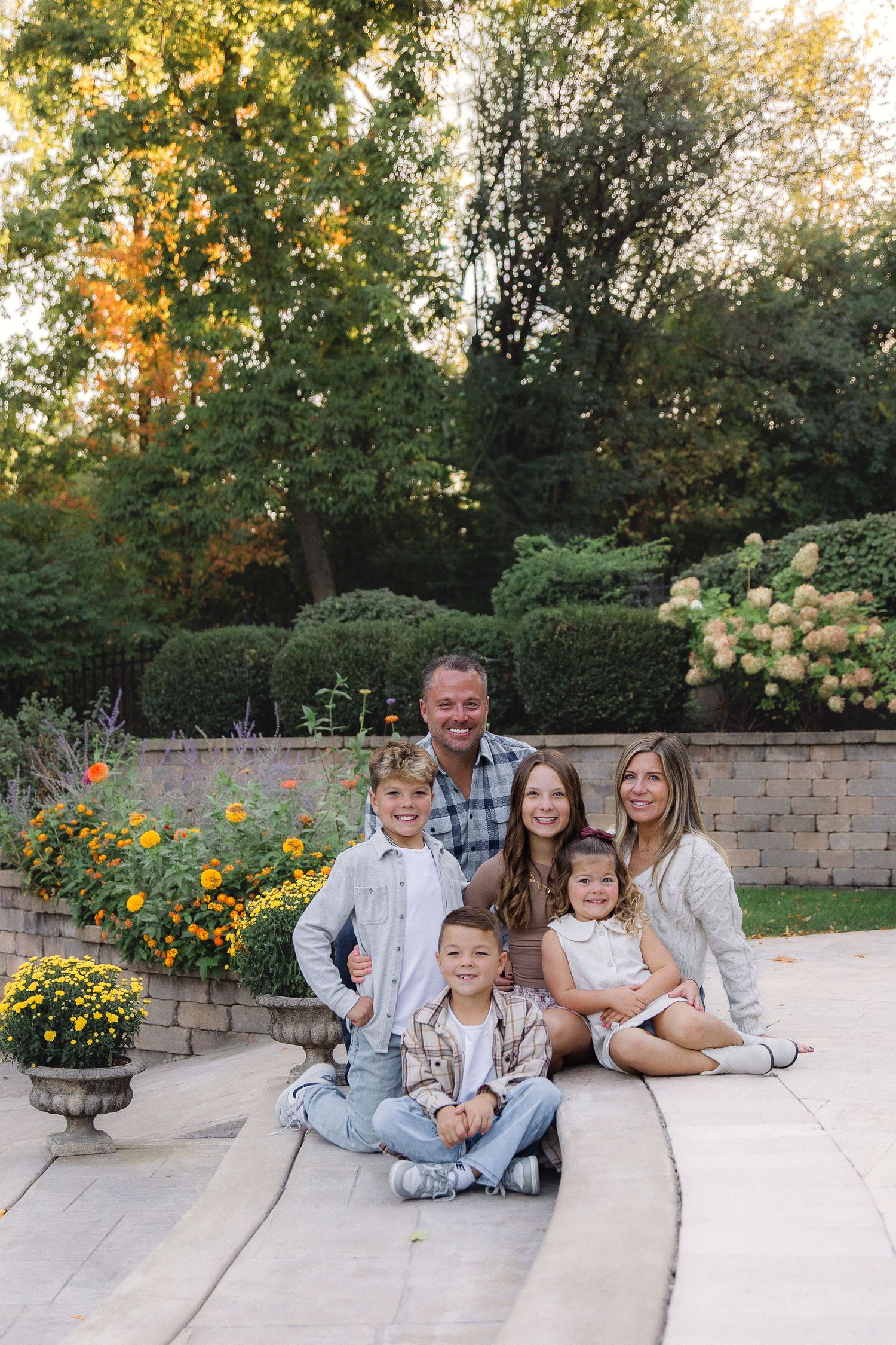 A group portrait on stone steps with autumn foliage and flowering bushes creating a natural backdrop.