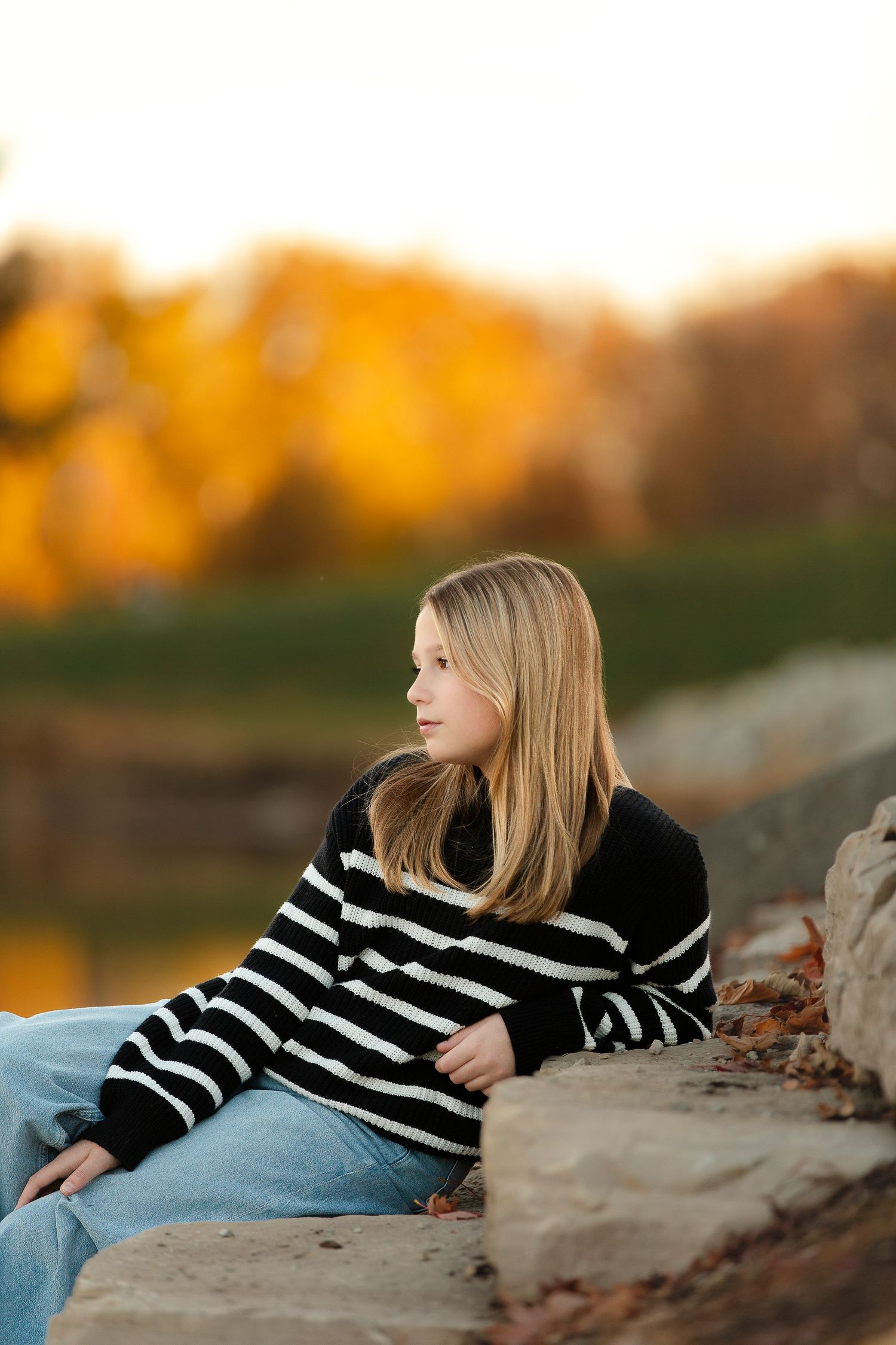 Person in black and white striped sweater lounging on rocks during golden hour.